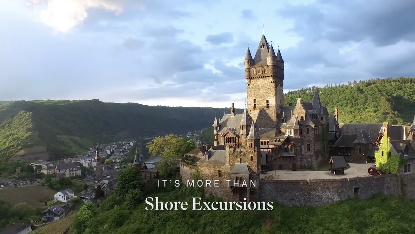 A castle on a hilltop overlooking a small town with green hills in the background.