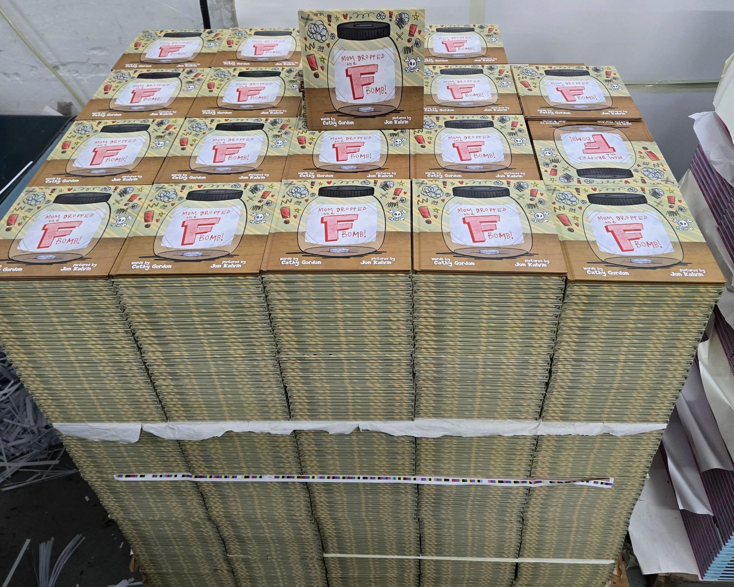 Finished copy of Mom Dropped the F-Bomb displayed on a pallet of newly printed books during the self-publishing journey.