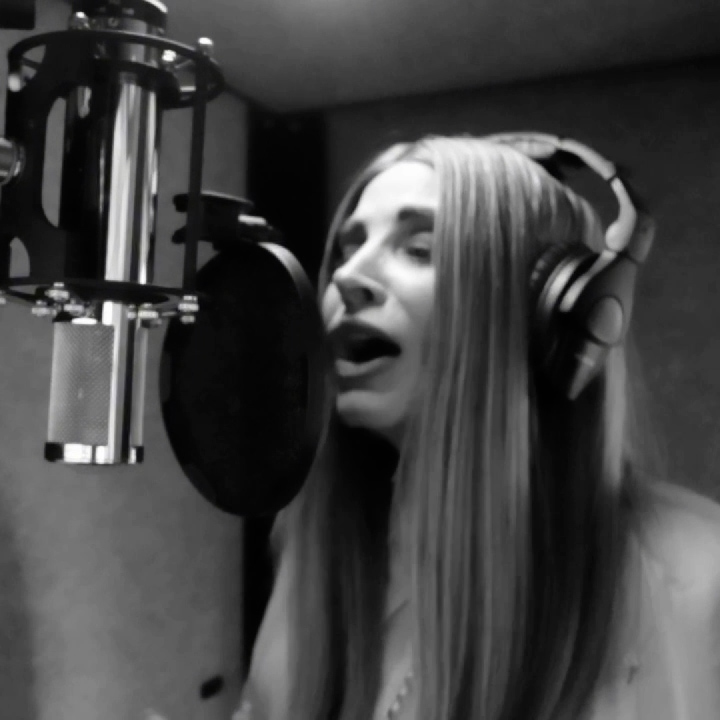 Julia Blum wearing headphones while recording vocals in her studio.