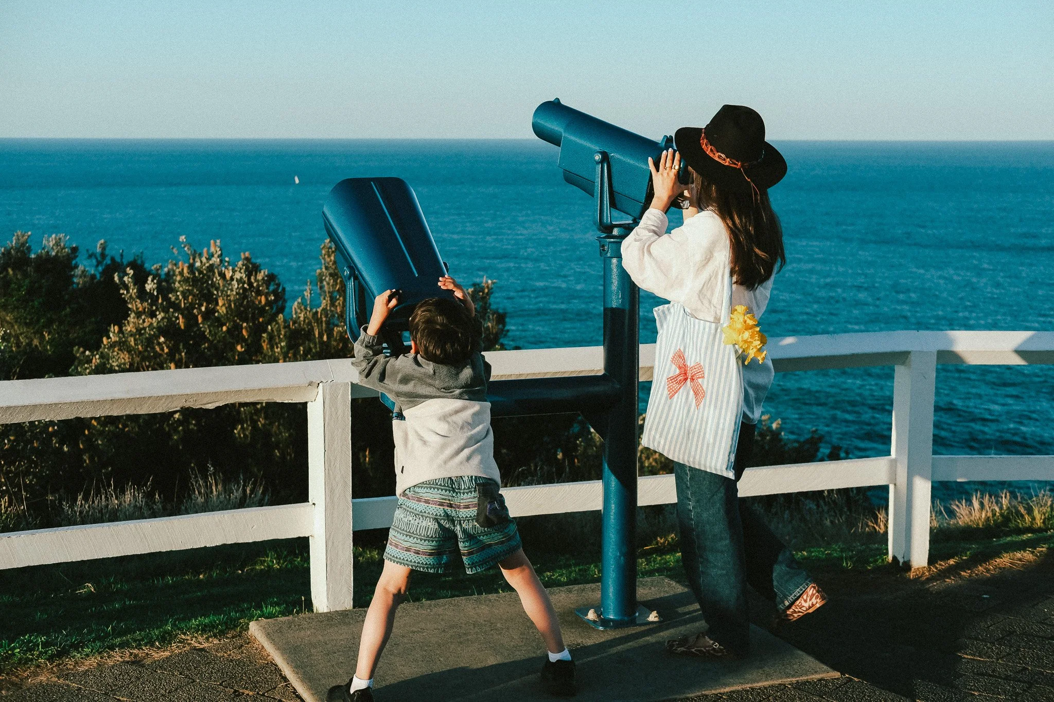 Mum and son looking through telescopes at a mountain lookout