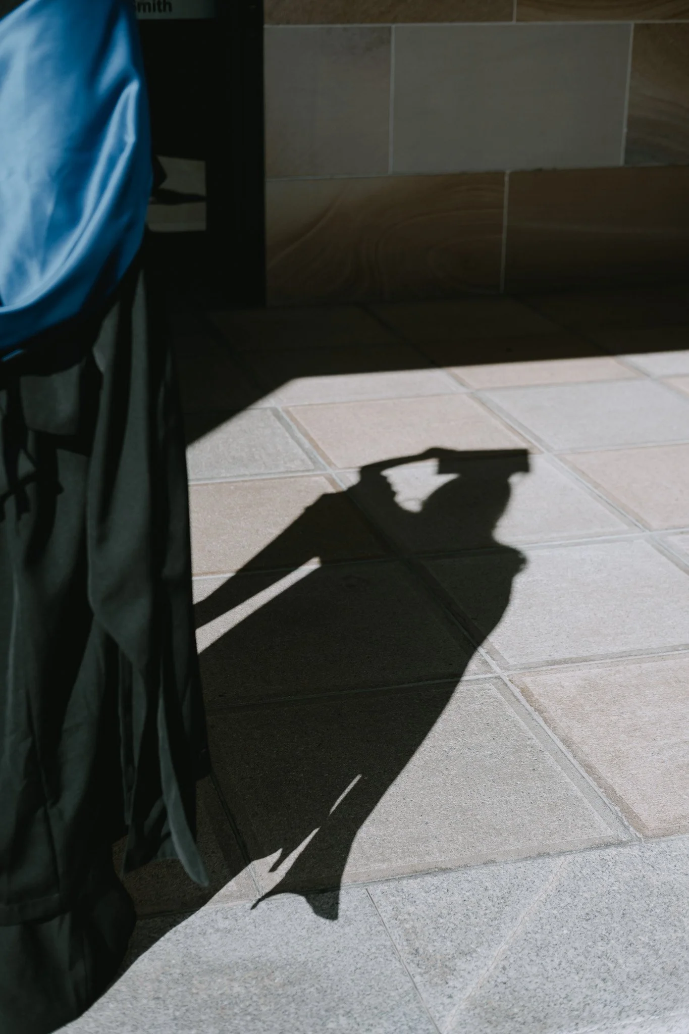 Shadow of University of Queensland graduate cast on the ground as they adjust their mortarboard