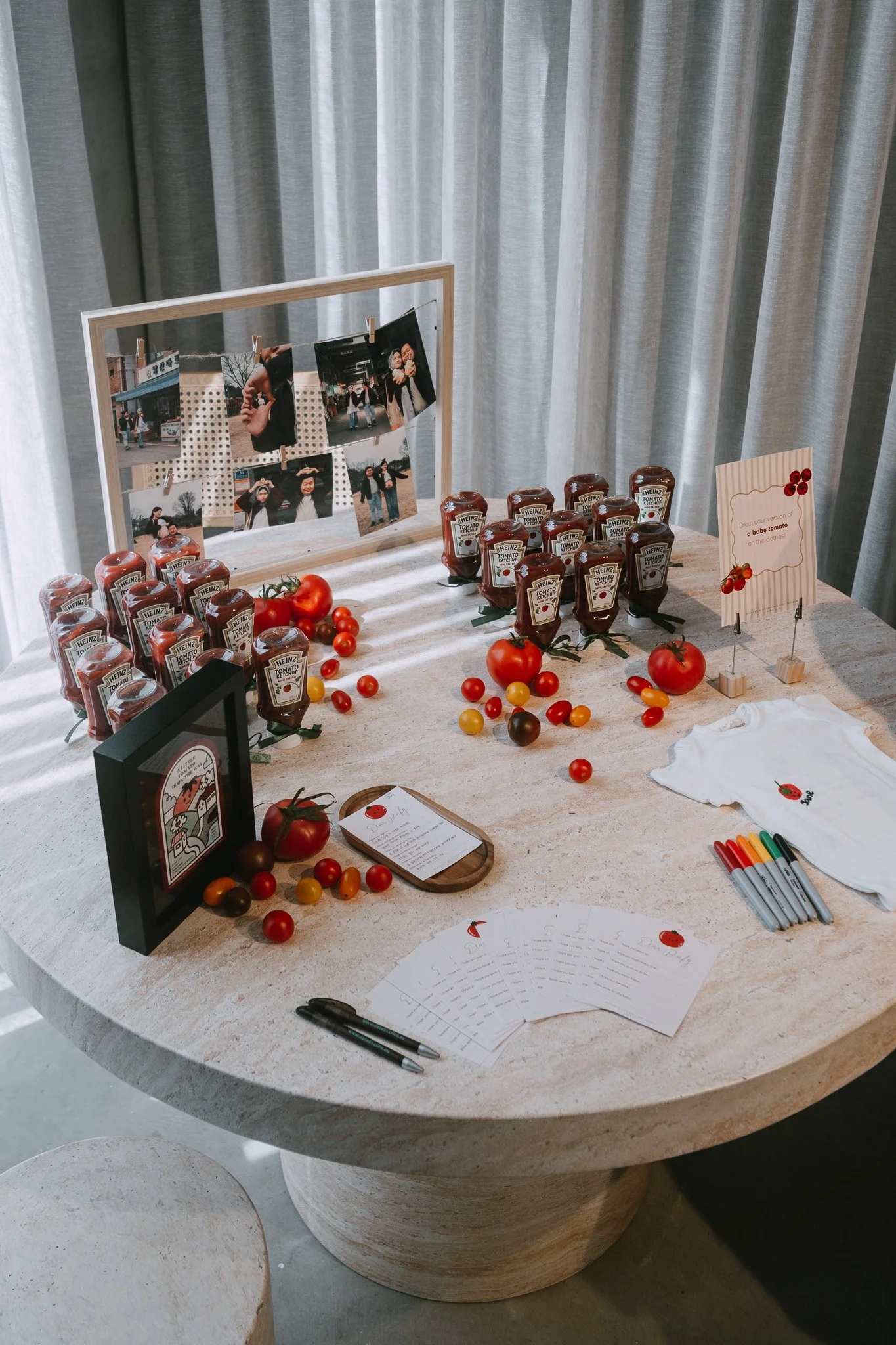 Styled table display featuring Heinz tomato sauce bottles, whole and cherry tomatoes, and photographs arranged on round stone table