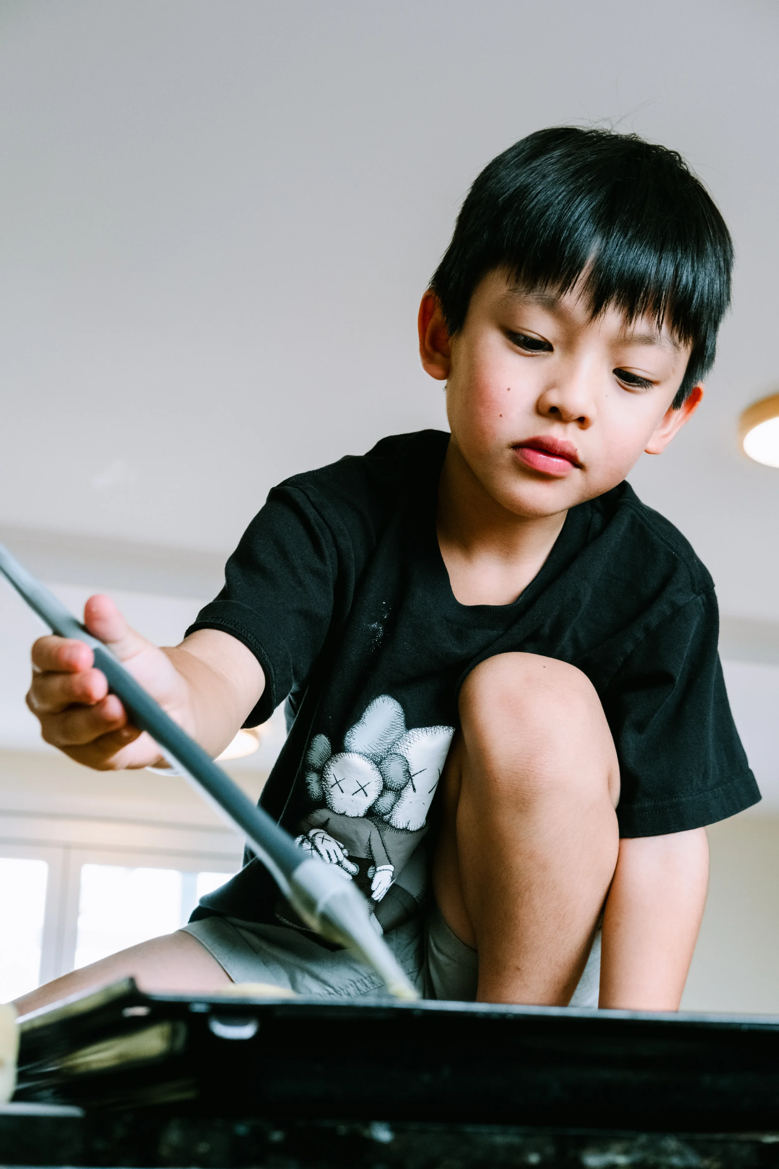 Young boy holding a spatula and stirring in a frying pan on the stovetop