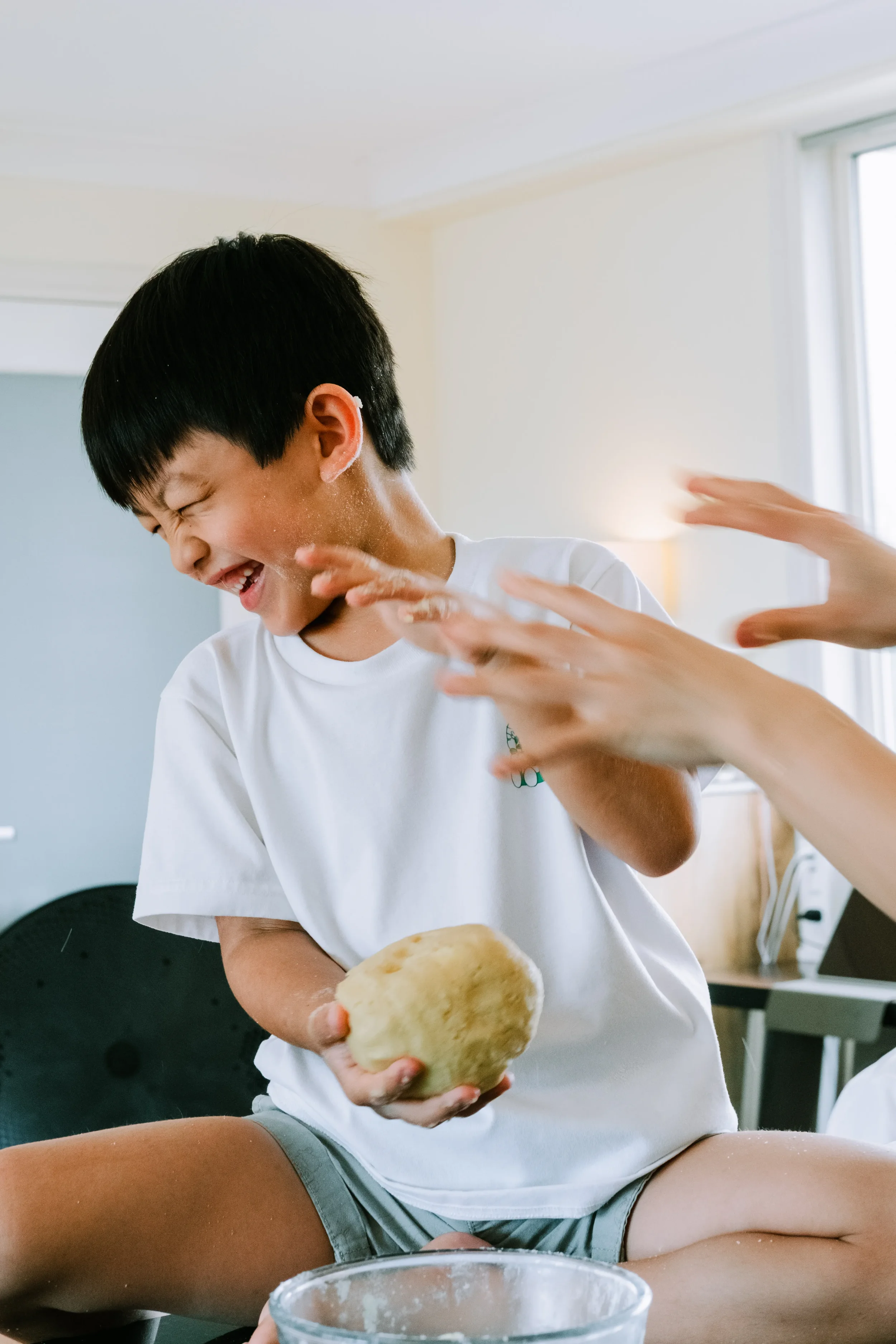 Young boy laughing mid-play with Mum in the kitchen