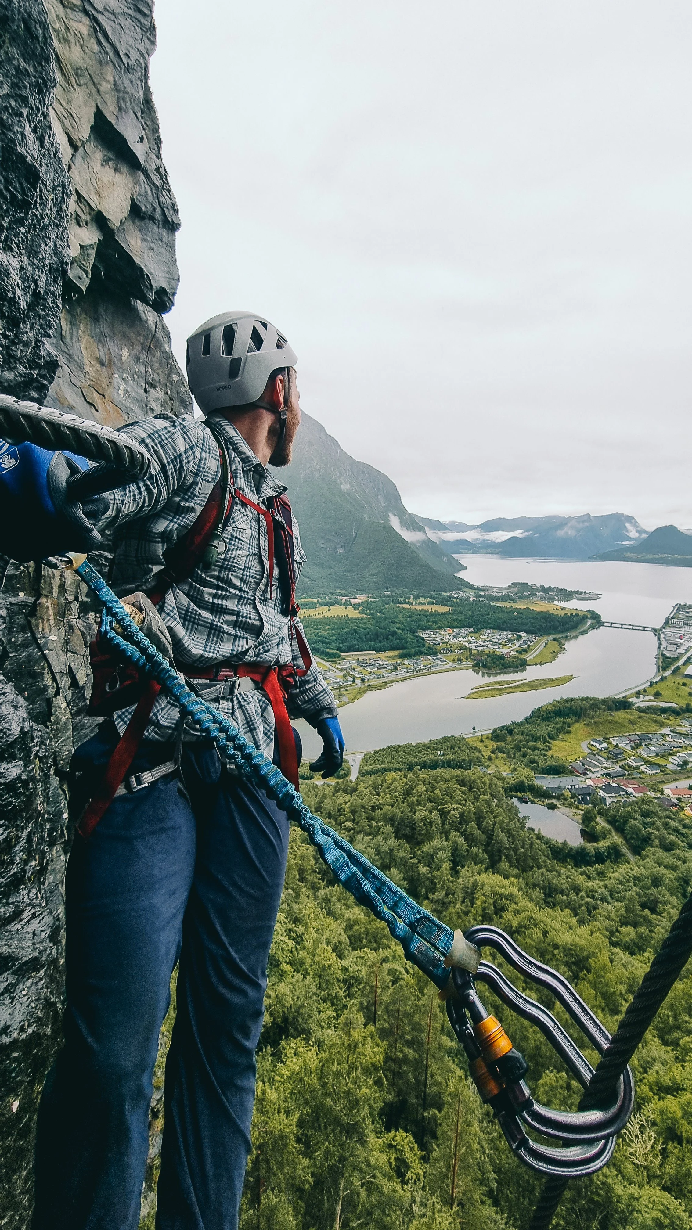 Mann ser utover Åndalsnes mens han klatrer Via Ferrata Vestveggen.