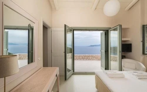 Cozy bedroom with open balcony doors overlooking the ocean