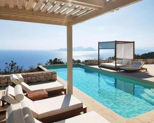 Luxury poolside area overlooking the ocean with lounge chairs, a shaded cabana, and scenic views of the sea and distant mountains.