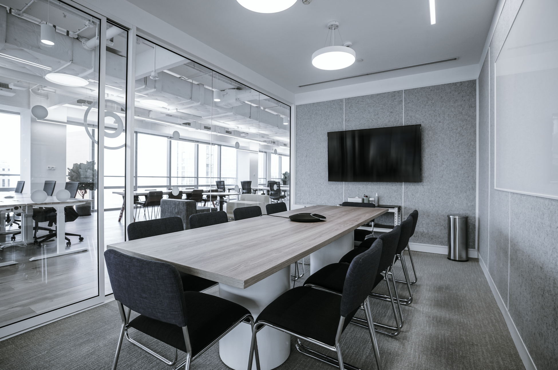 LED Electrical Wholesalers - Modern conference room with a large wooden table, black chairs, a flat-screen TV on the wall, and a glass-walled office area in the background.