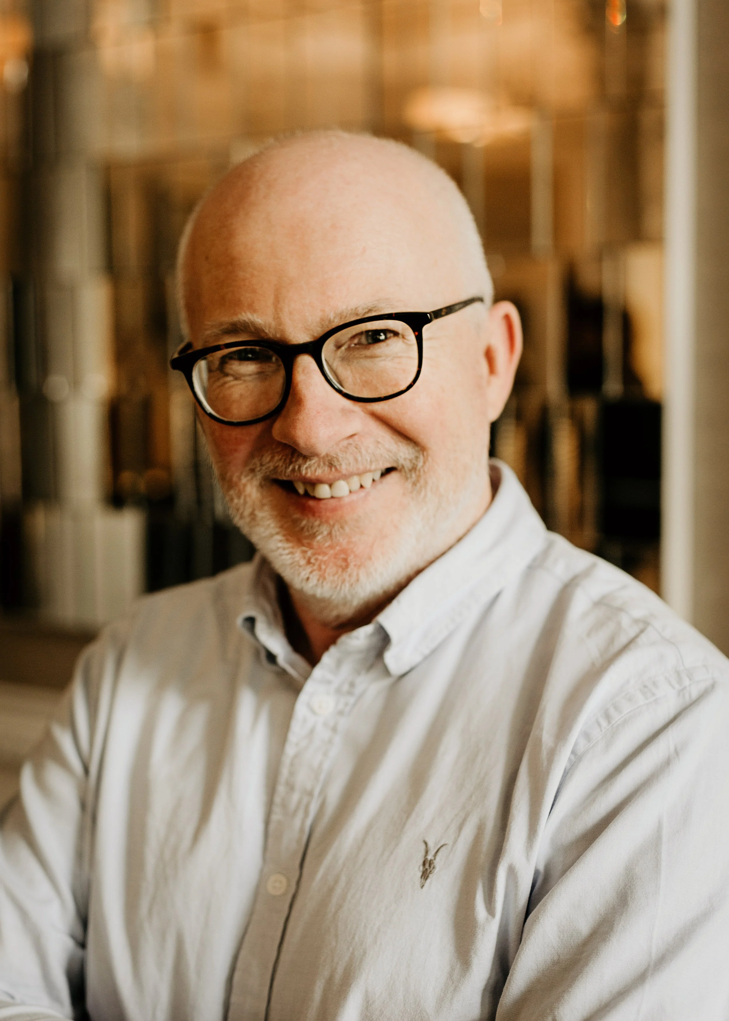 A middle-aged man with glasses, a white shirt, and a trimmed beard, smiling.