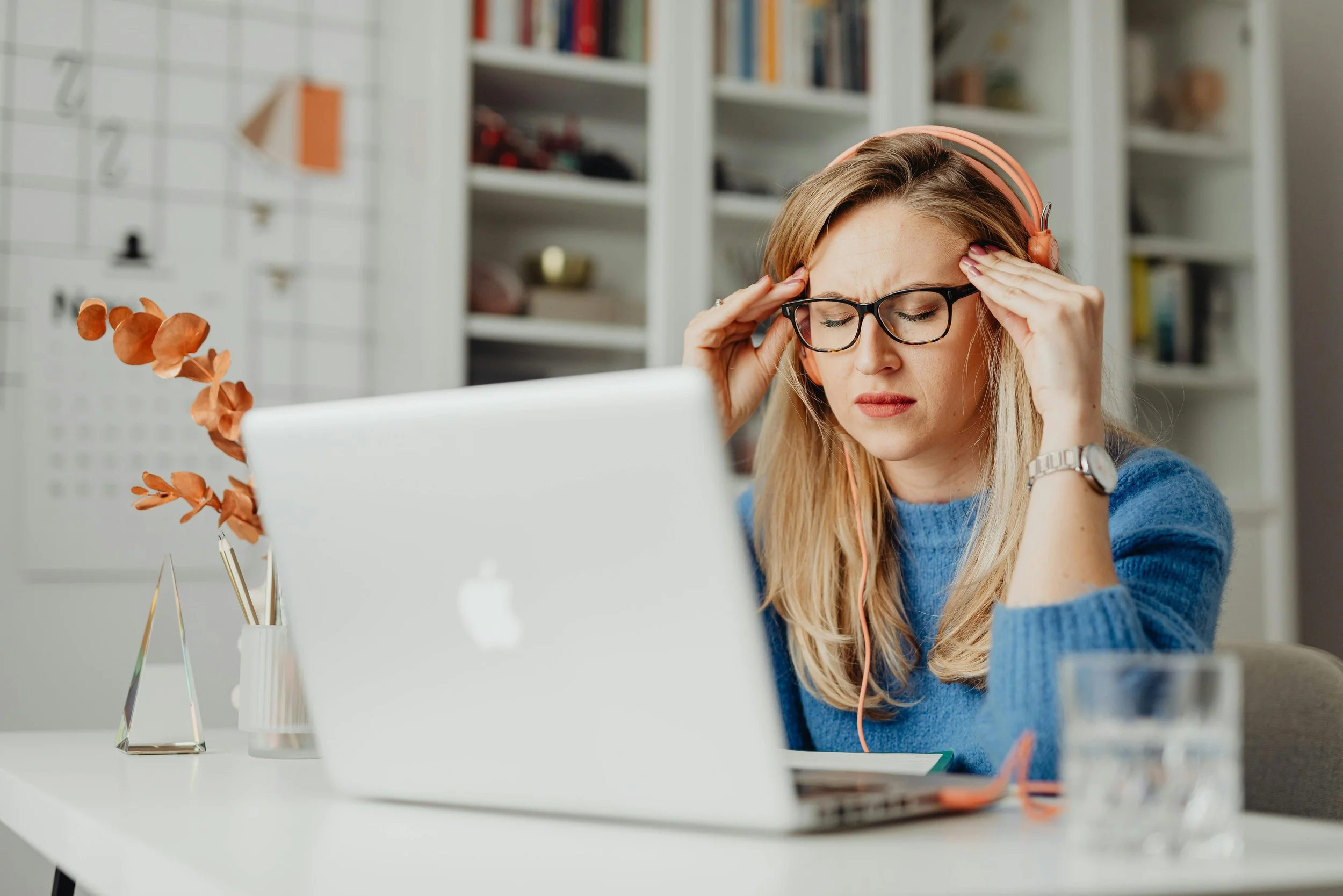 Woman at laptop holding her head