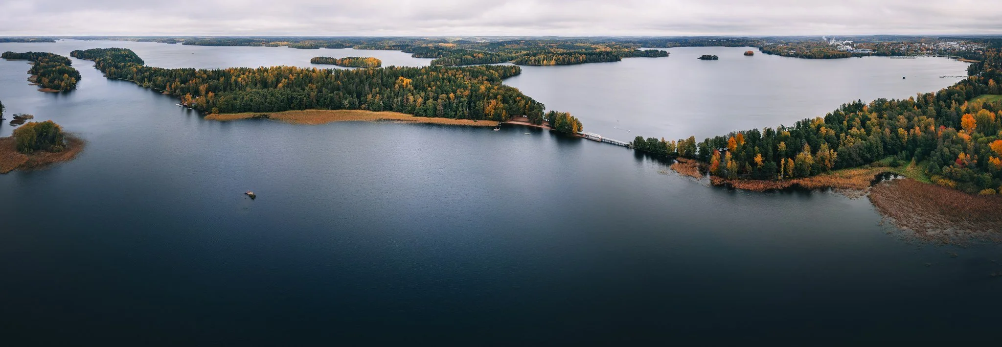 Valokuva suuresta järvestä, jonka ympärillä on puita ja saaria, ja taivaalla pilvinen sää, otettu ilmasta.