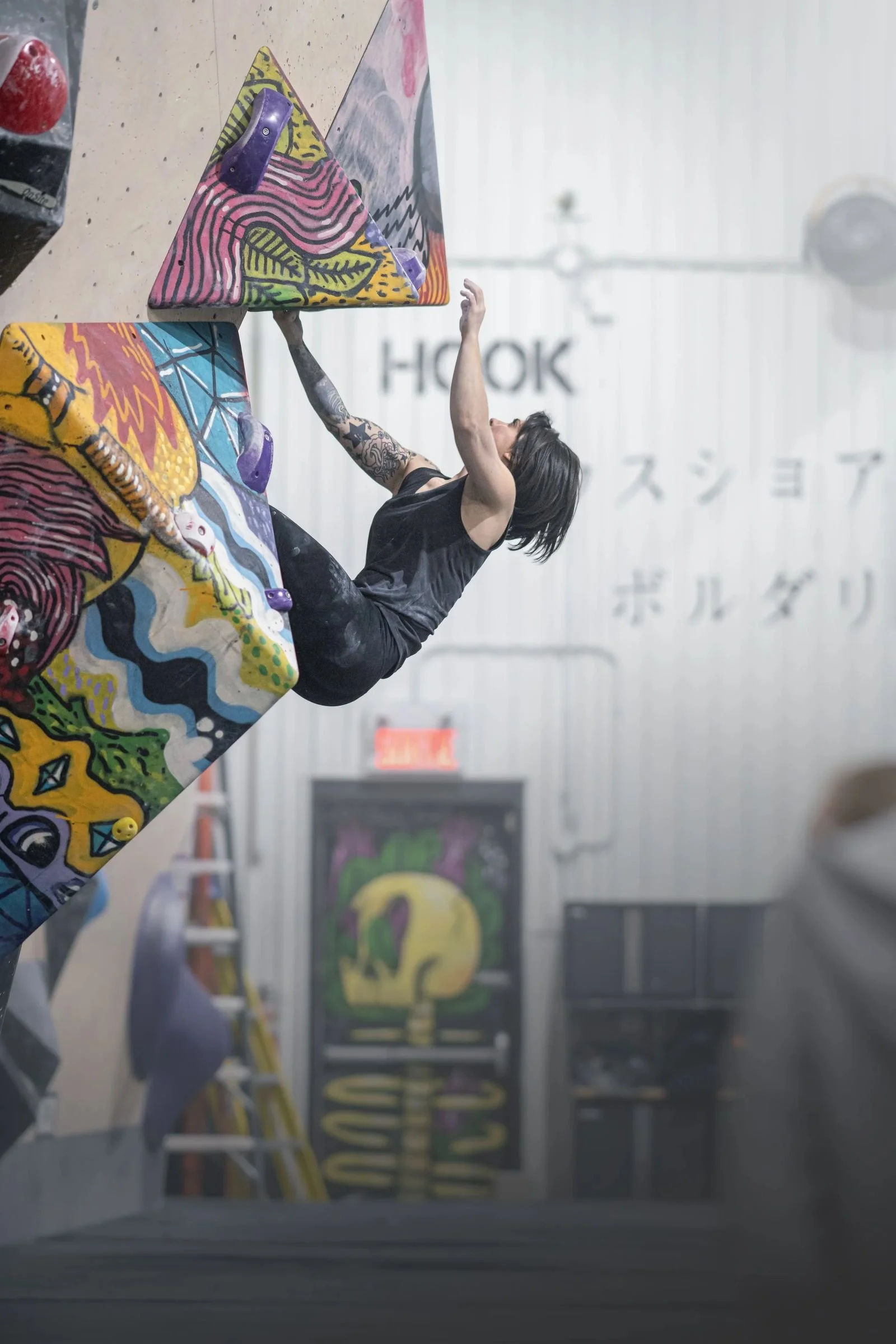 Grimpeur sur un mur de bloc du Hook pendant une compétition