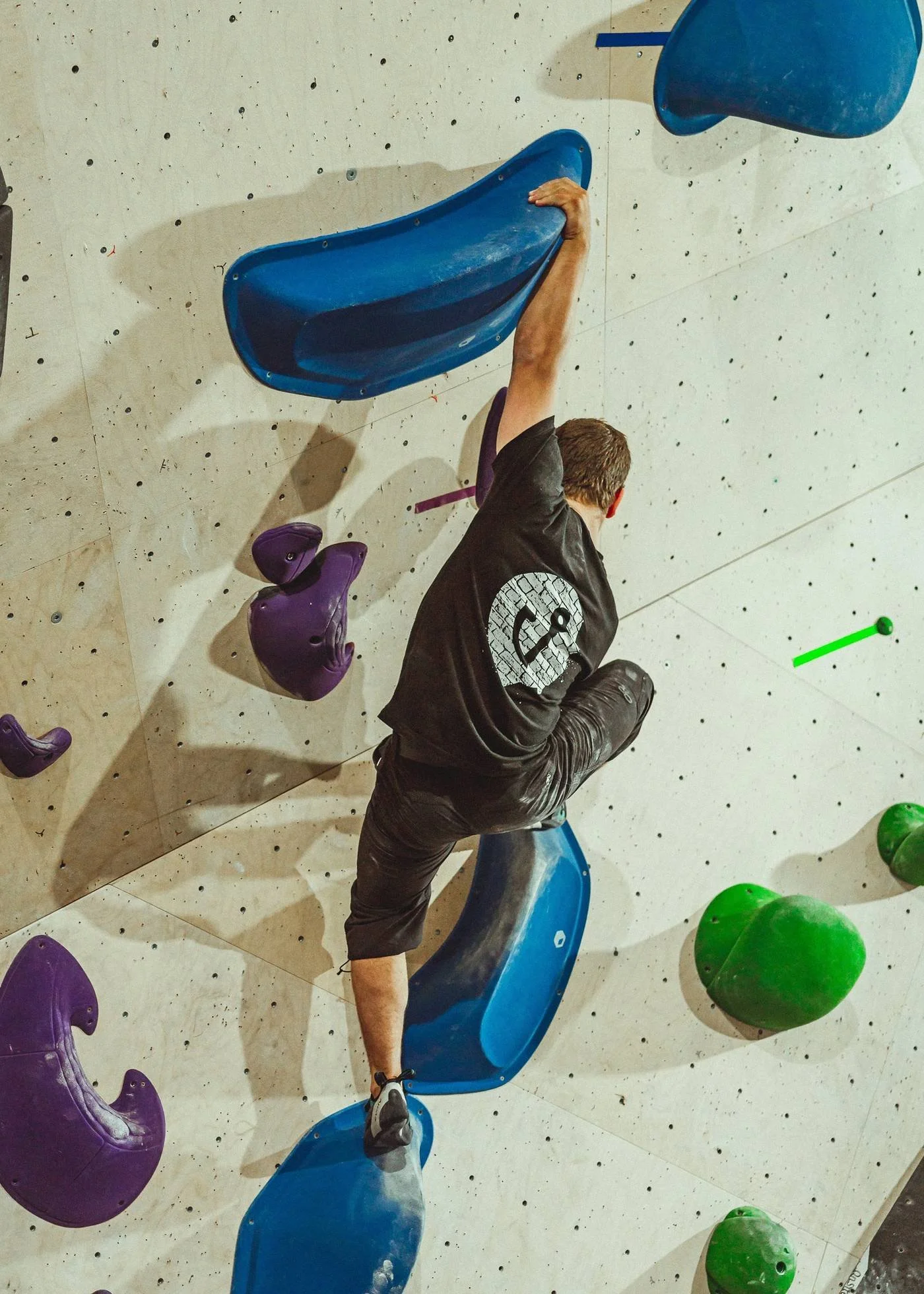 Grimpeur qui agrippe une grosse prise bleue au centre d'escalade Hook
