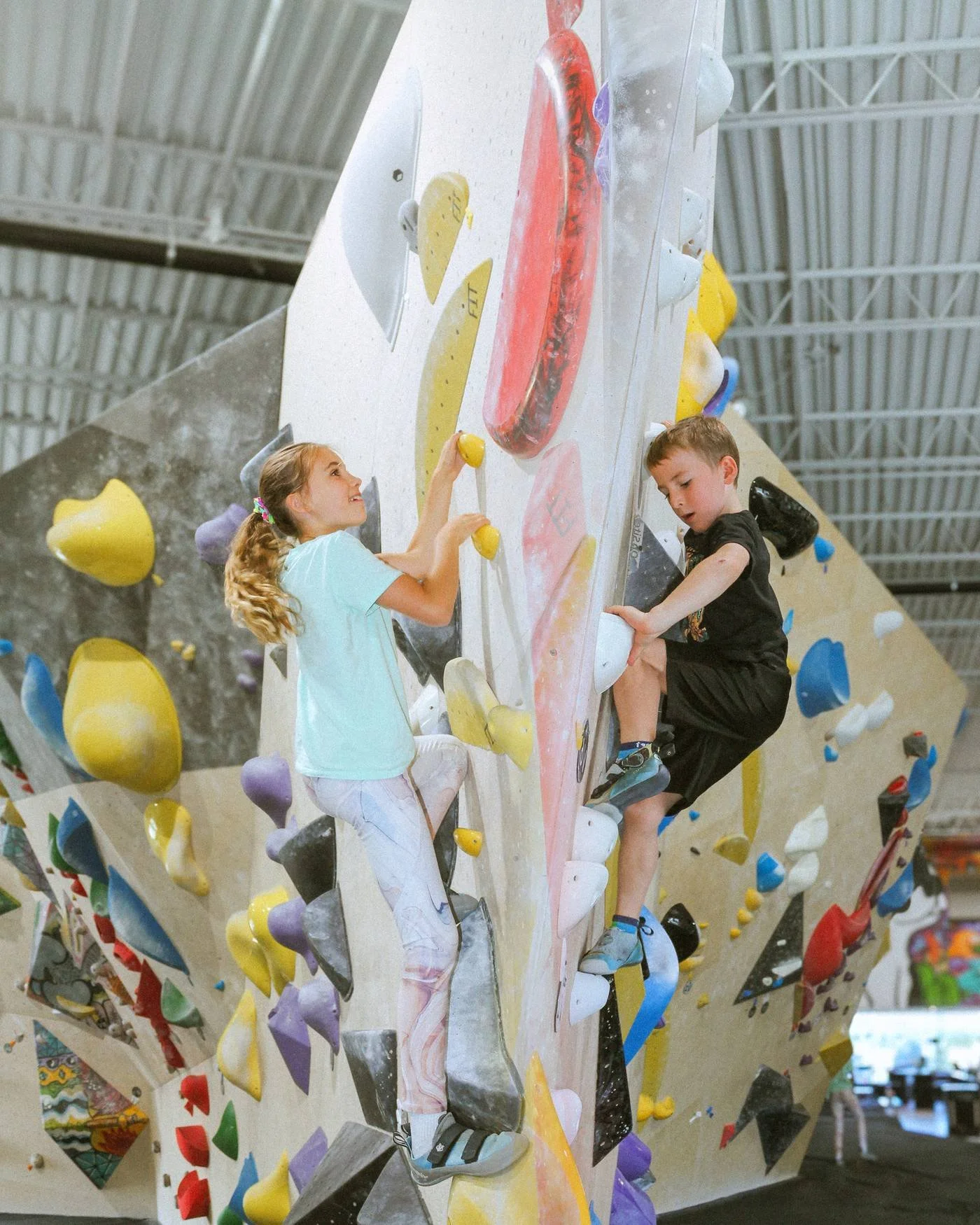 Enfants qui grimpent ensemble sur un mur de bloc coloré au camp de jour