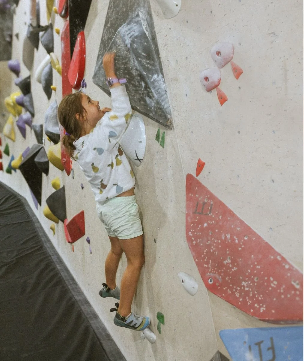 Jeune enfant qui grimpe un bloc pendant un cours d'escalade pour enfants au Hook