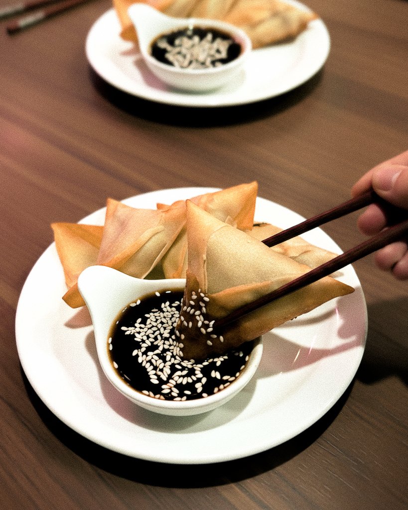 Rouleaux de printemps à tremper dans une sauce soja garnie de graines de sésame, servis avec une petite coupelle de sauce.