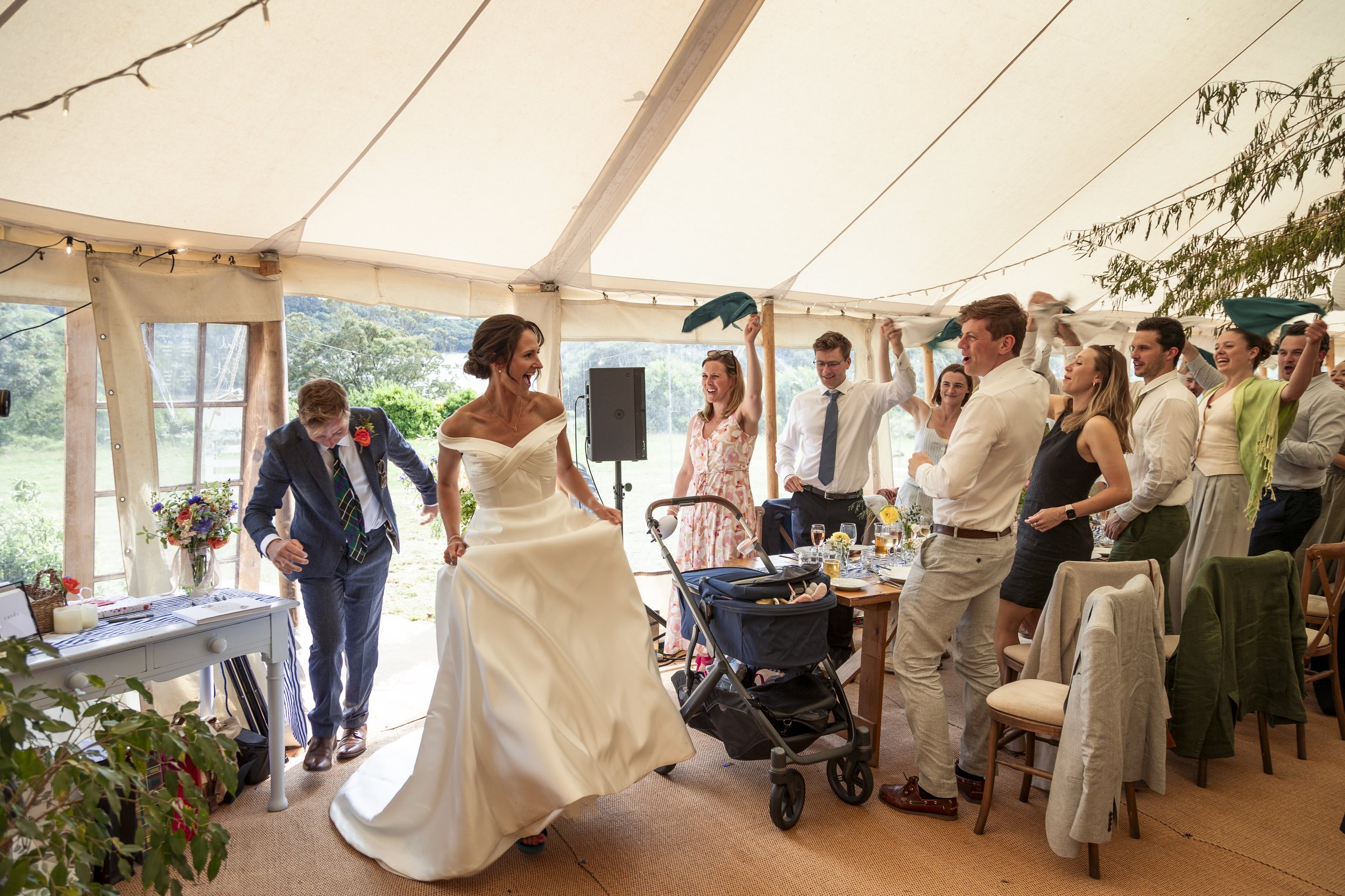 Bride dancing with guests at a wedding reception inside a tent.