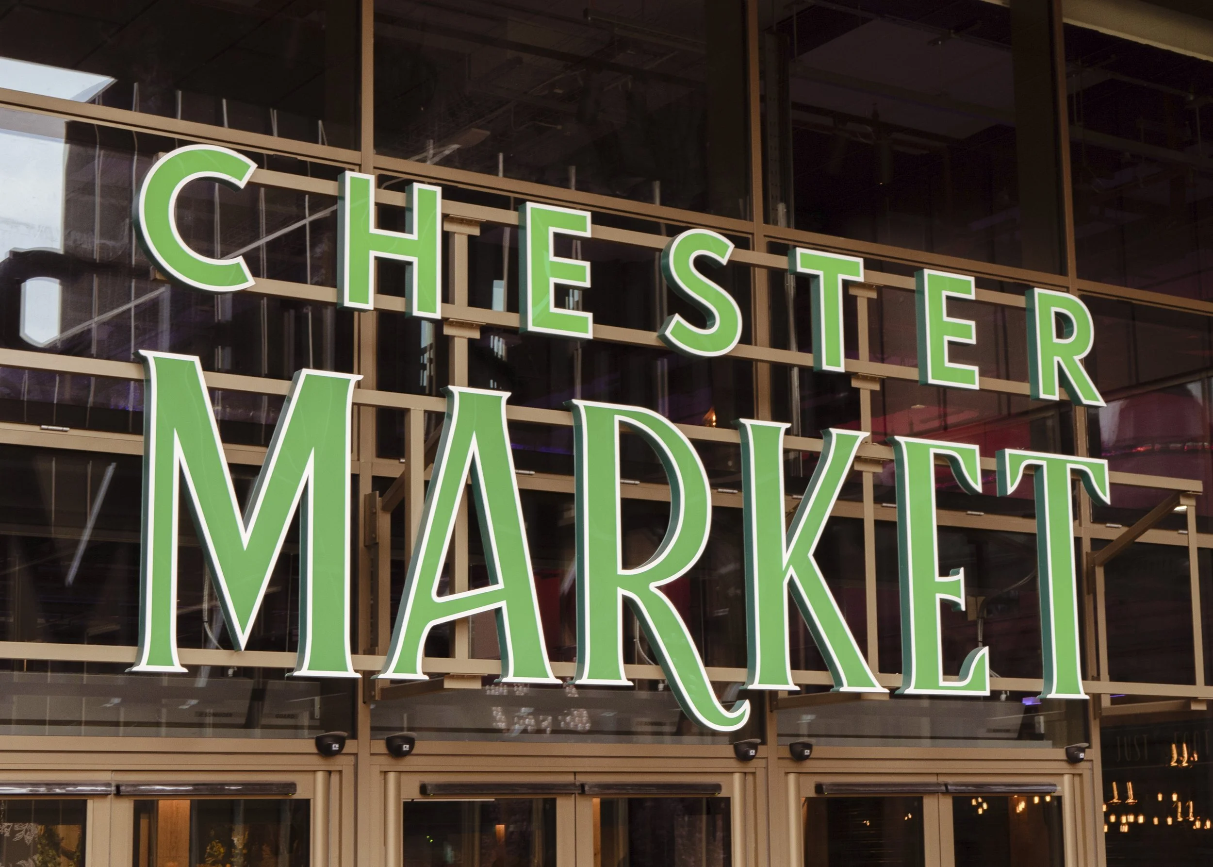 Info sign for Chester Market with large green letters on a building facade