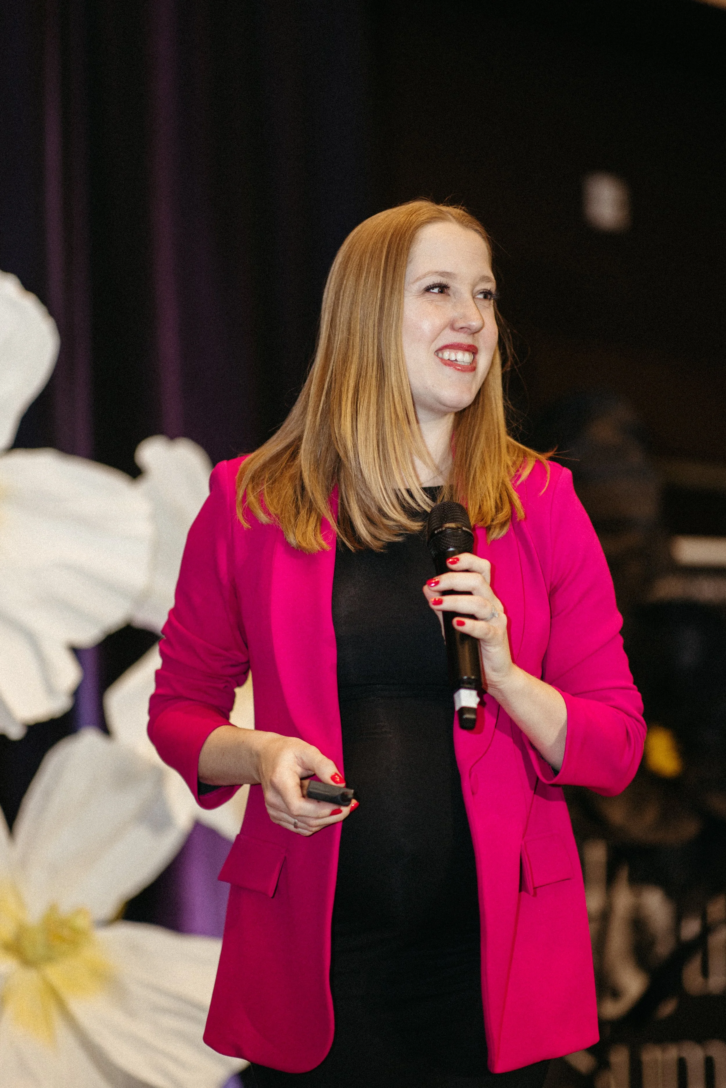 Rebecca Lynn Lyons speaks at an event on stage in front of an audience of over 500 people