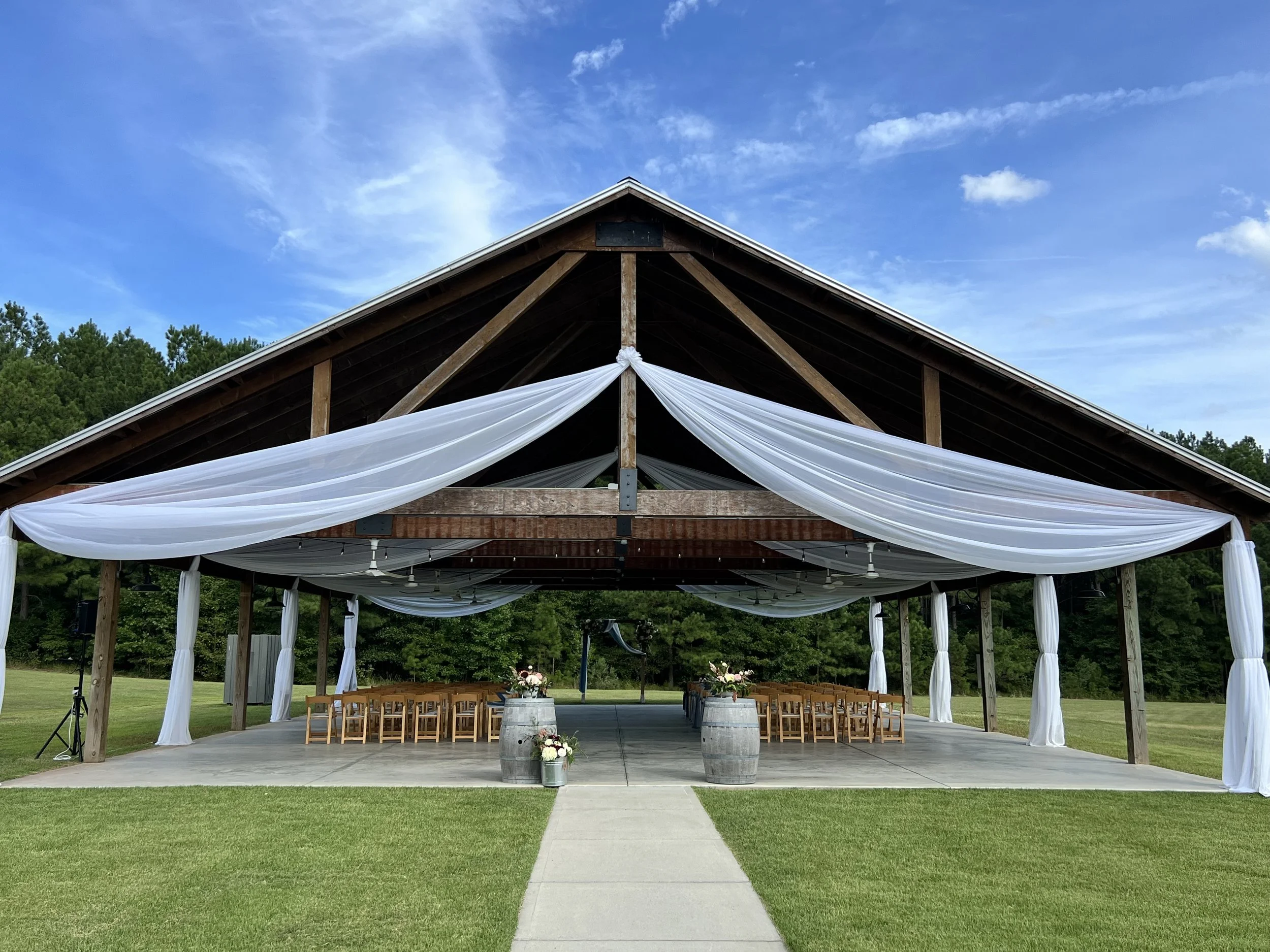 The wedding pavilion draped with white fabric and flower arrangements at Oakland Farm