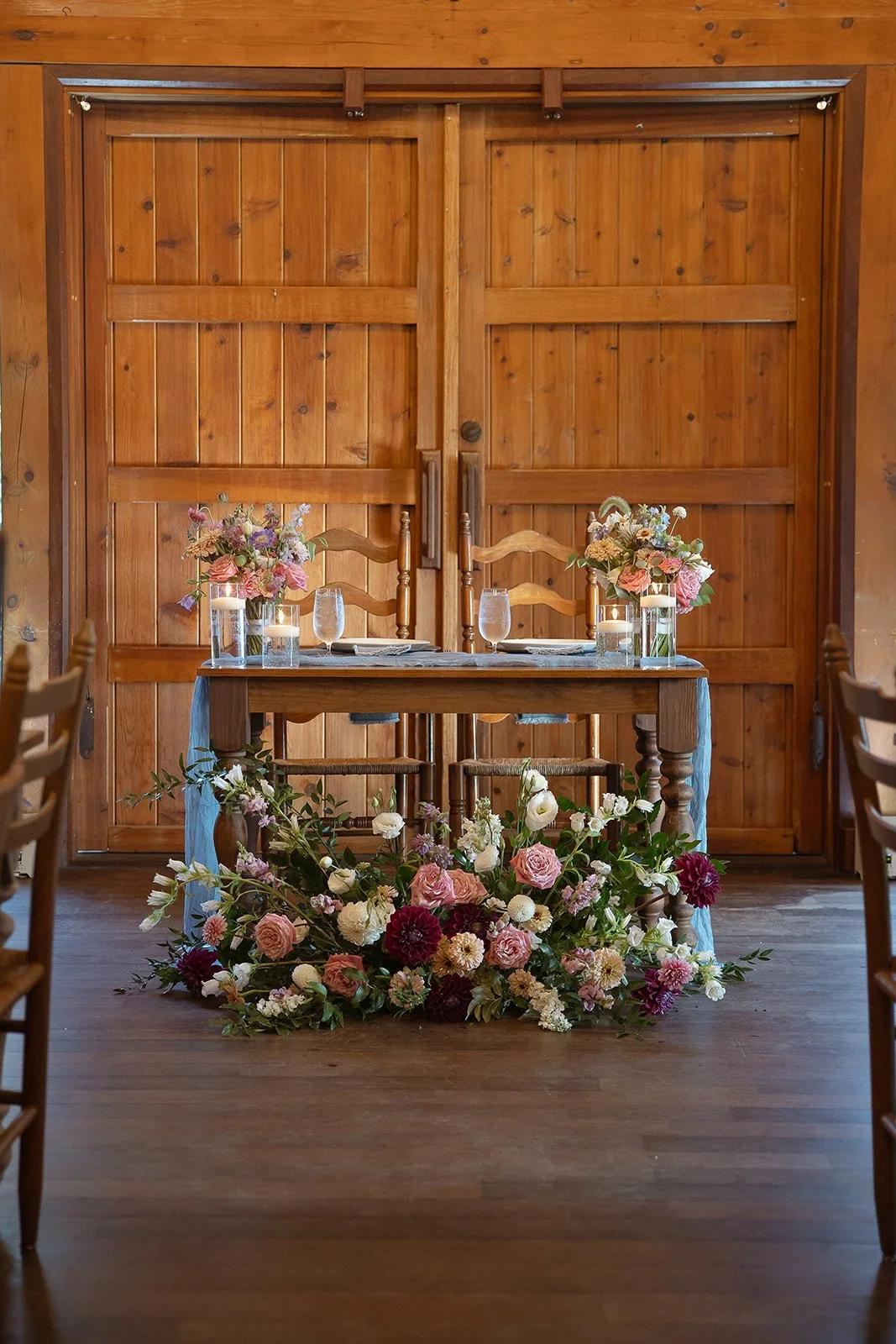 Pink and purple summer wedding flowers in front of a Sweetheart table at the Barn at Valhalla