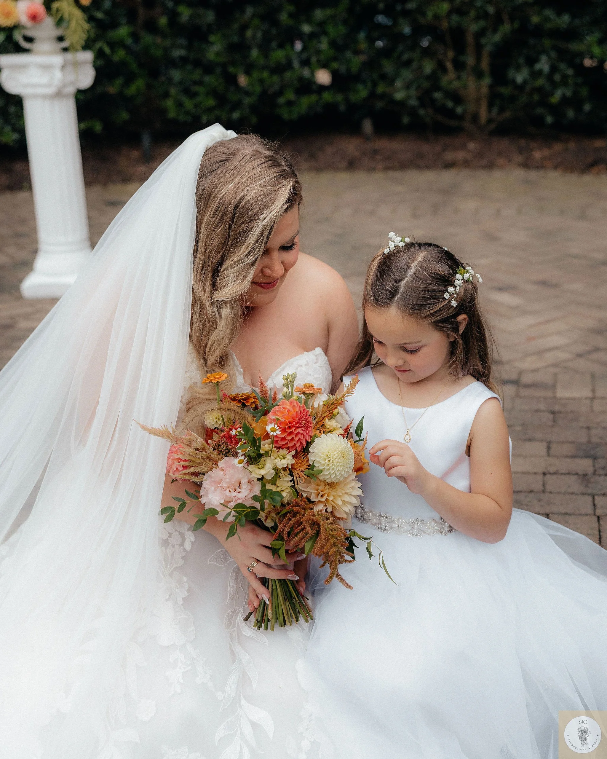 A Raleigh, NC bride and flower girl admire a fall bridal bouquet