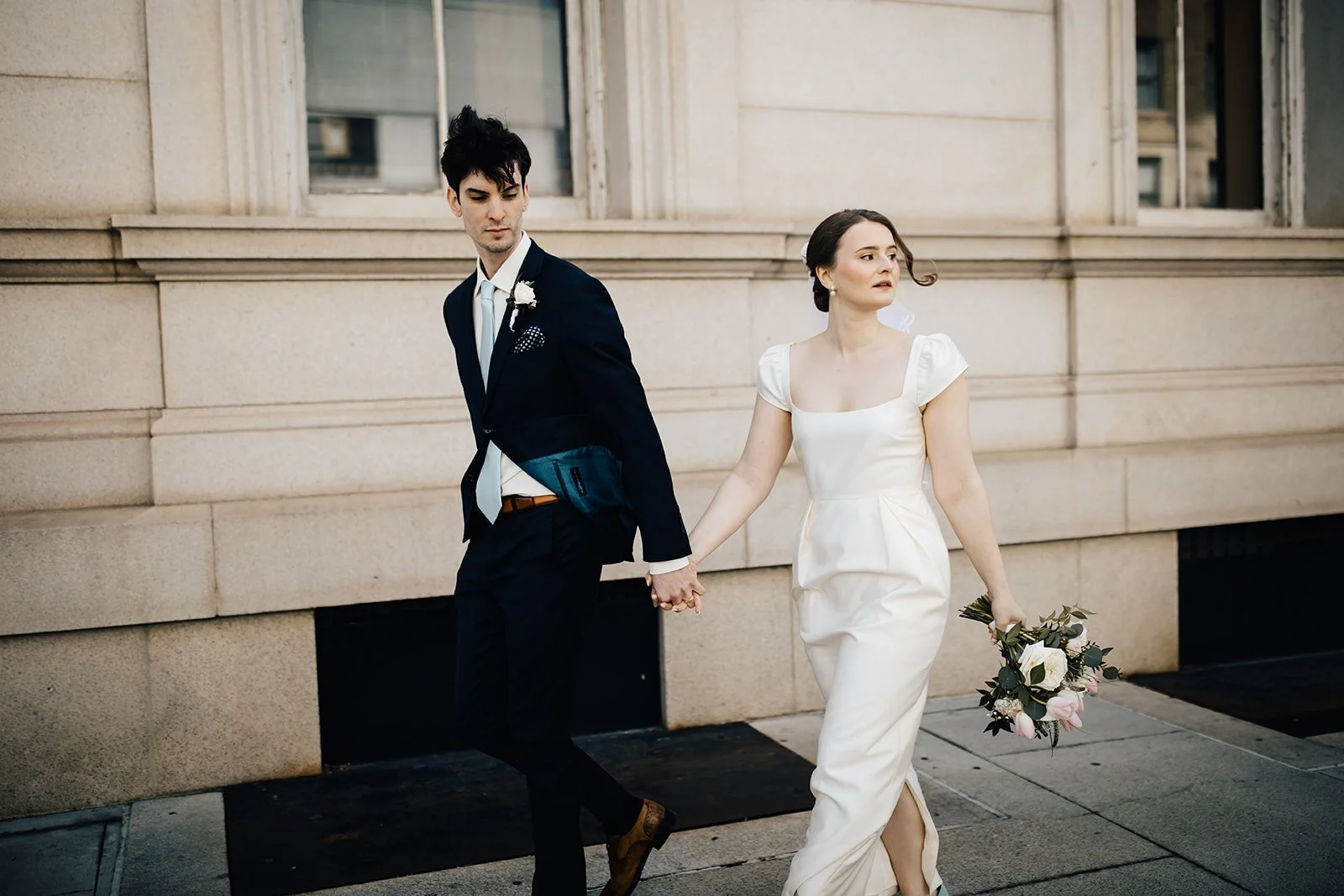 Bride and groom walk Raleigh's downtown streets with flowers after a courthouse microwedding