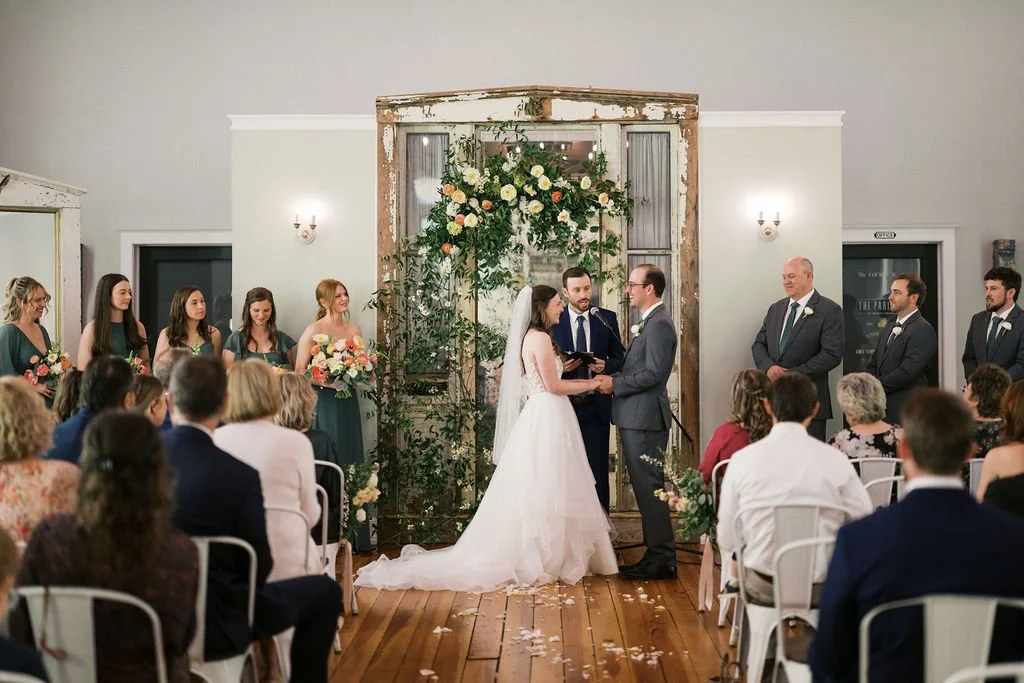Smilax vines and early spring blooms climbing antique mirror altar backdrop at the Parlour at Mann's Chapel in Chapel Hill, NC