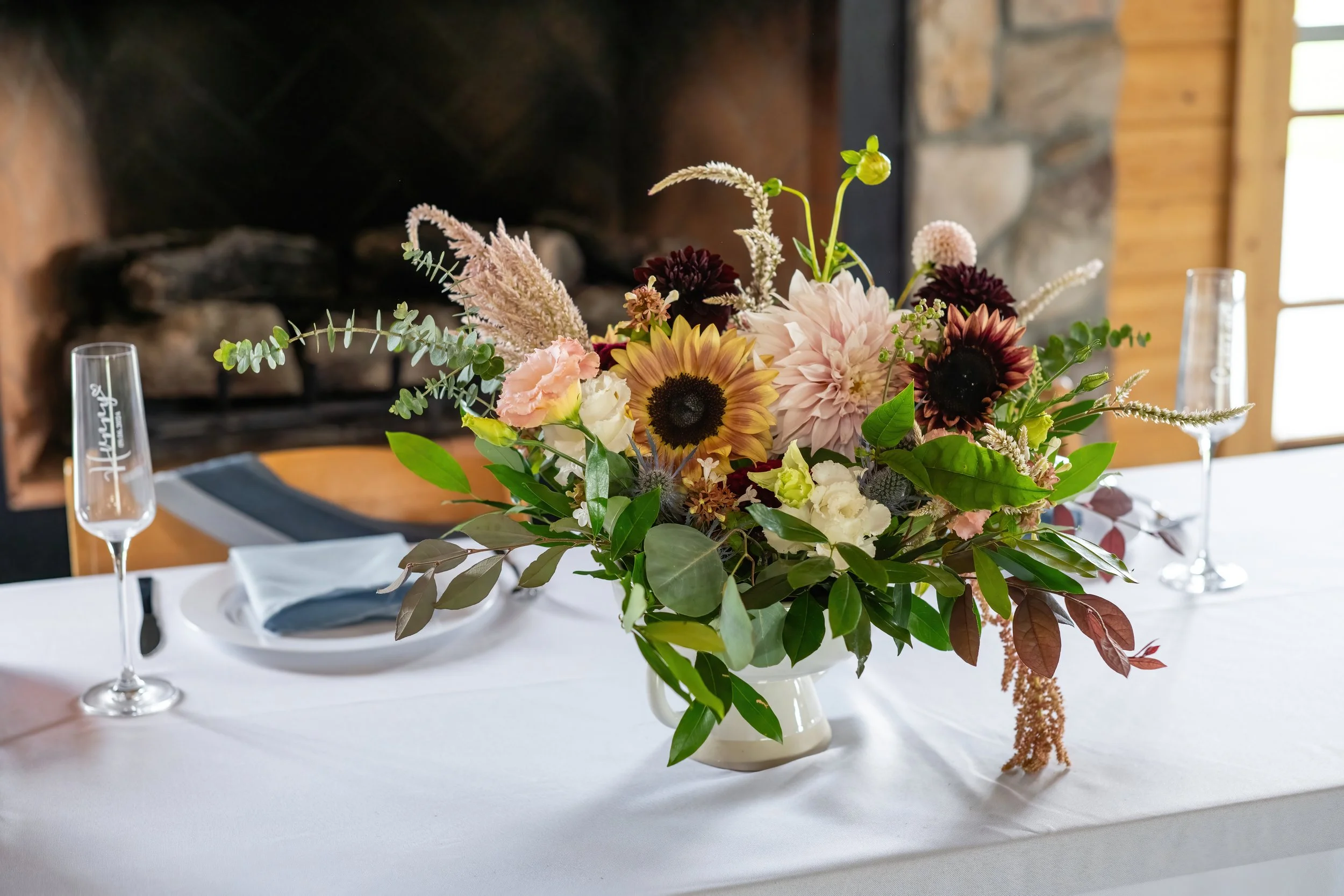 A fall dahlia and sunflower arrangement on a sweetheart table at Oakland Farm