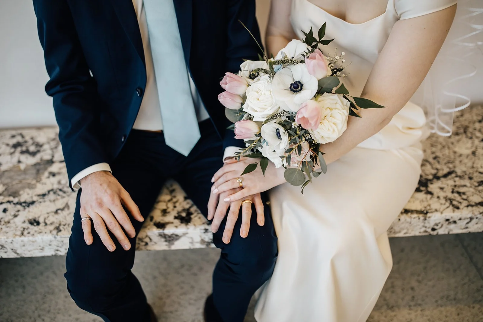 A closeup of a Raleigh bride and groom holding hands and a bridal bouquet for a downtown microwedding