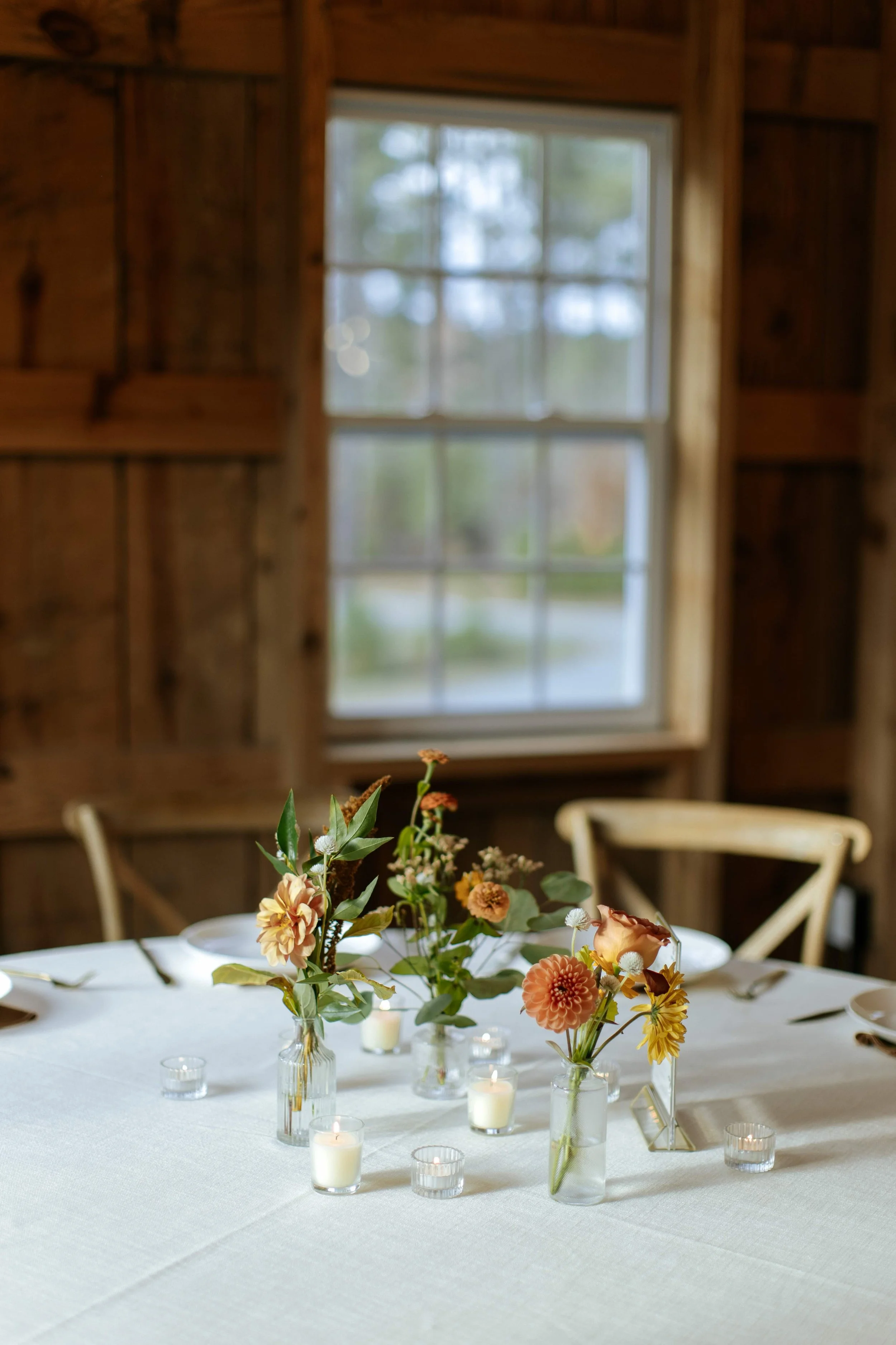 A cluster of fall themed bud vases cluster on a wedding reception table in NC