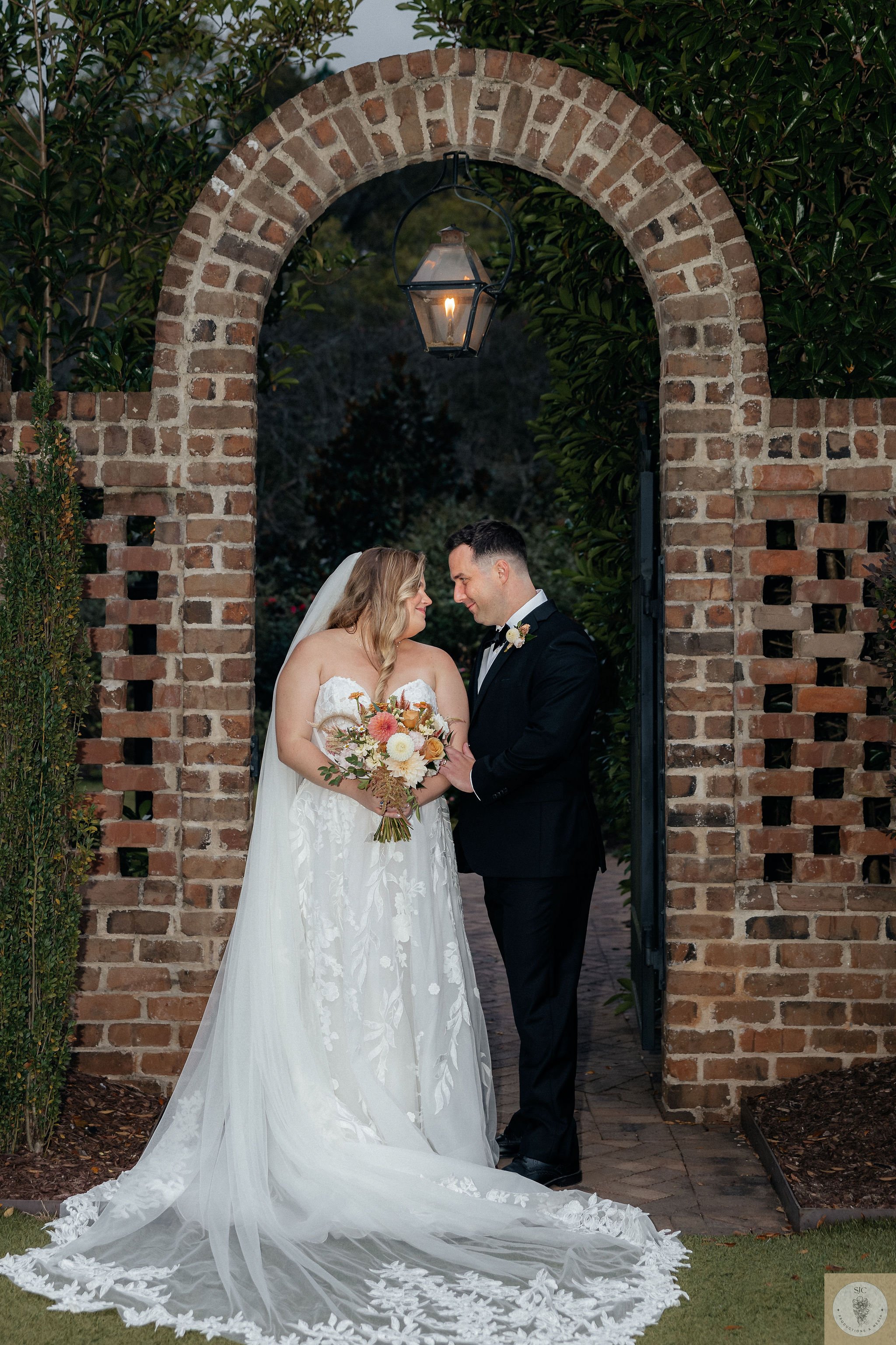 An October bride and groom pause under an arch at the Sutherland in Raleigh, NC
