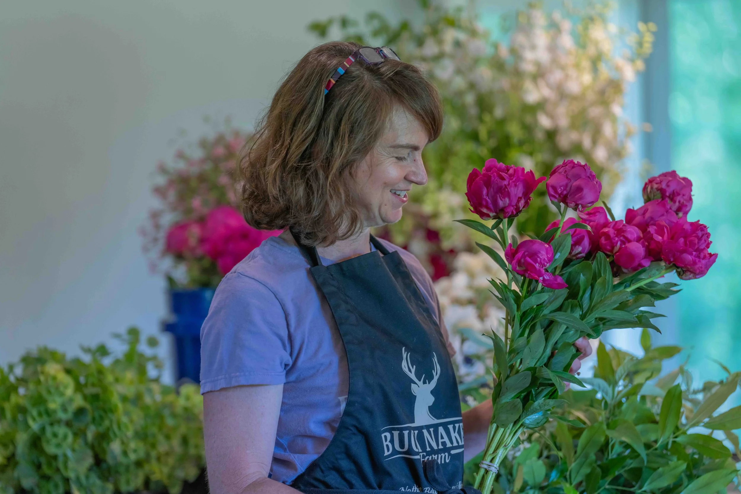 Buck Naked Farm owner Jennifer Howard poses with pink spring peonies