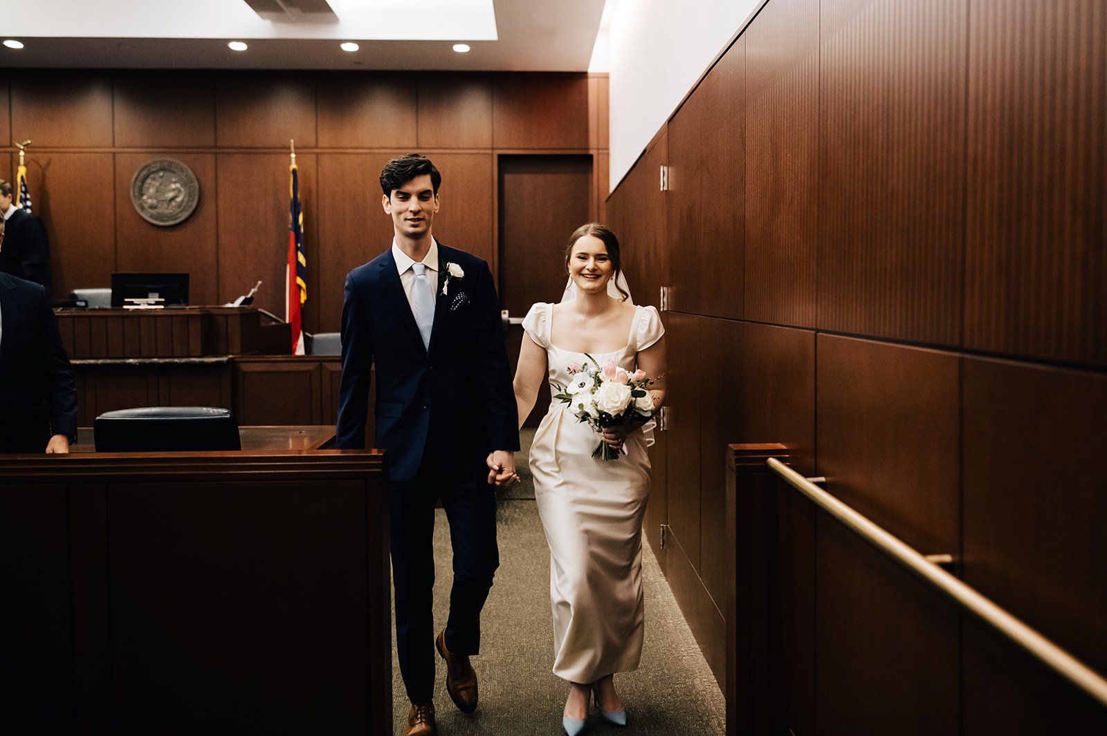A bride and groom hold hands after a microwedding at the downtown raleigh courthouse