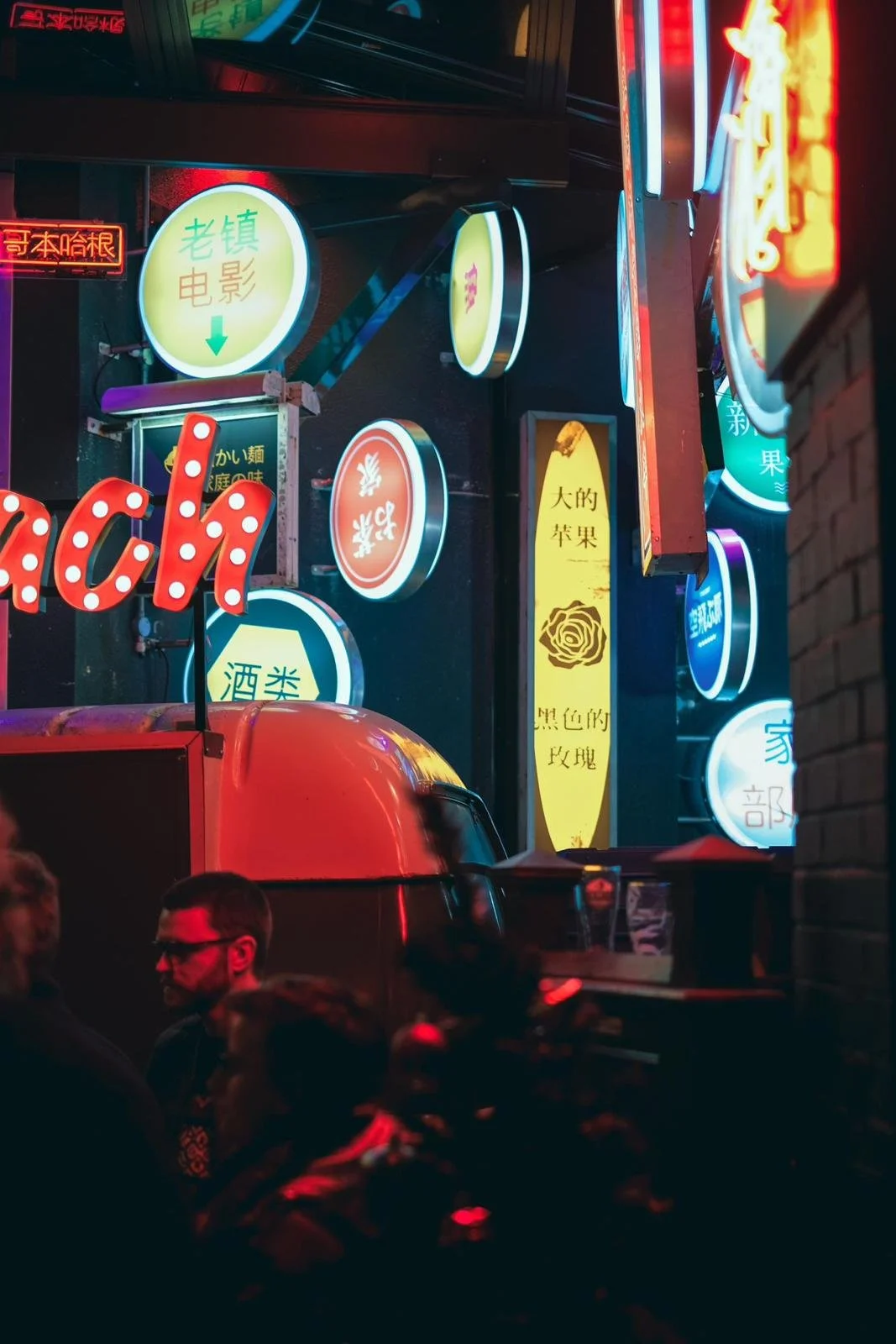 Night scene with neon signs in Chinese, colorful lights, and people in a busy street.