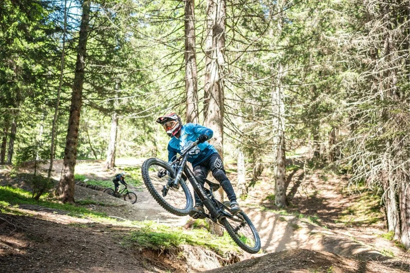 Moniteur-Guide VTT encadrant un groupe en montagne sur un itinéraire Enduro, avec un terrain technique et accidenté.