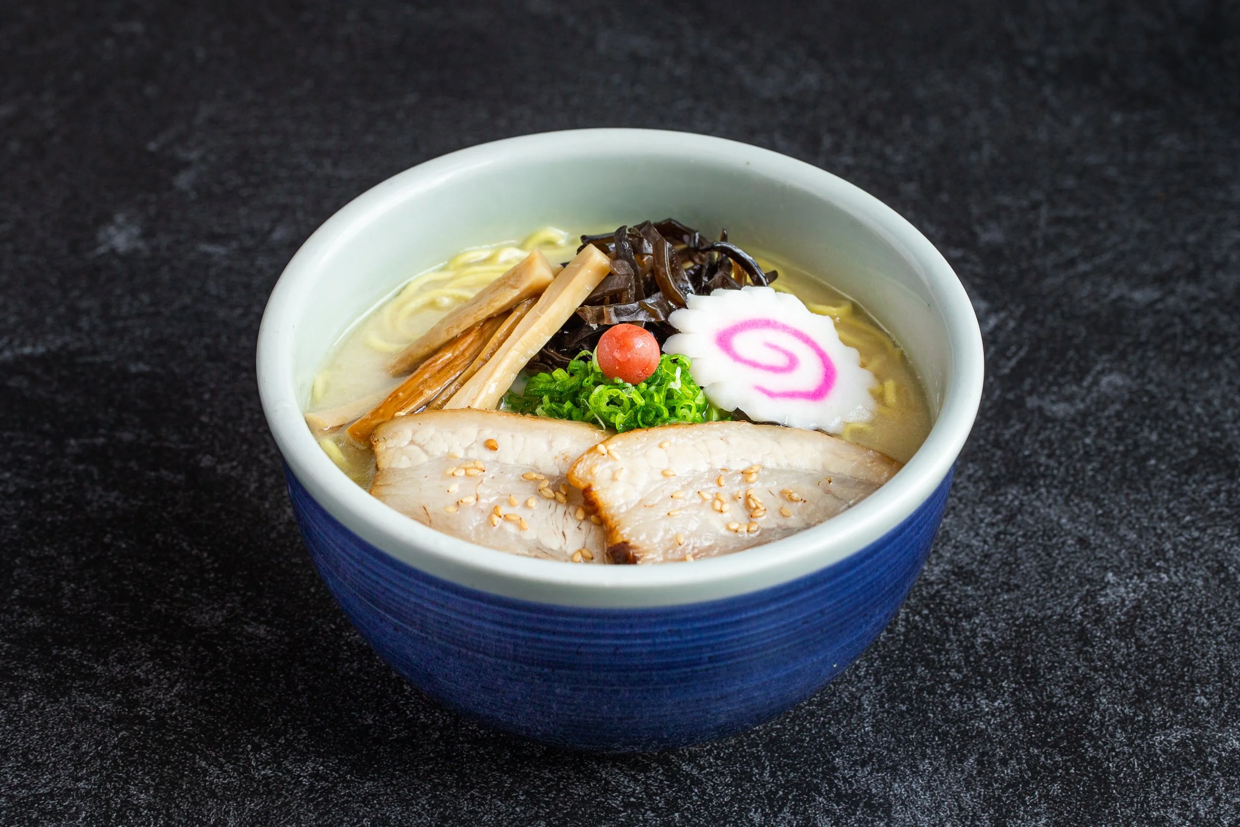 A bowl of shio ramen with cha-siu along with naruto, green onions, umeboshi, etc.