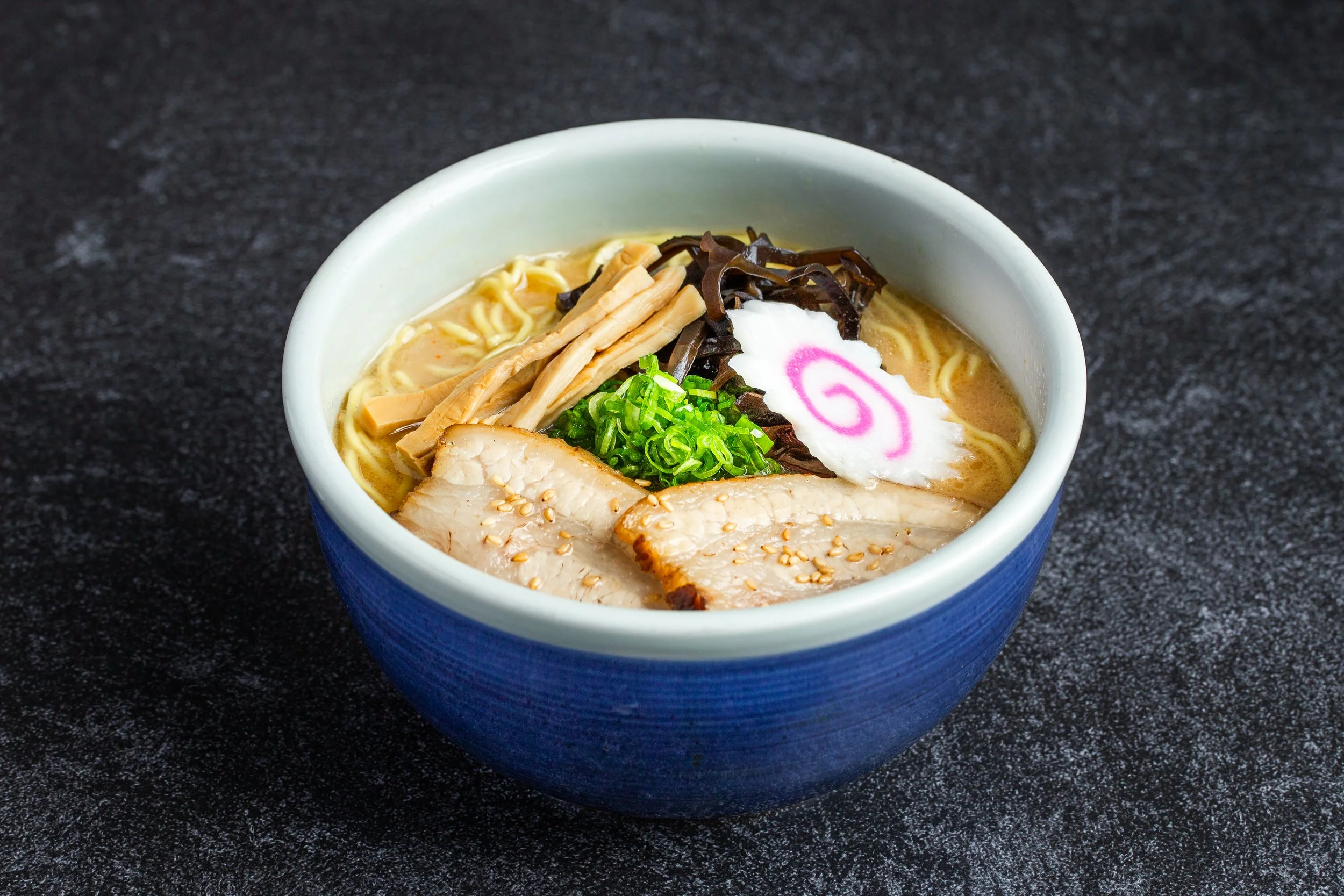 A bowl of miso ramen with cha-siu along with naruto, green onions, seaweed, etc.