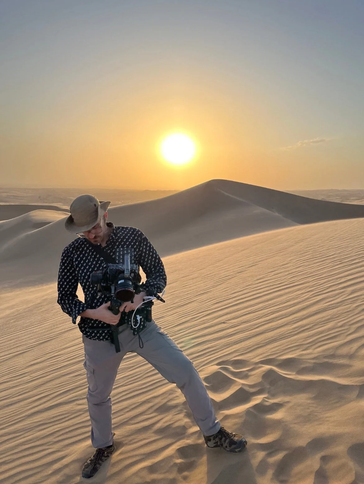 Camera man on sand dune at sunset
