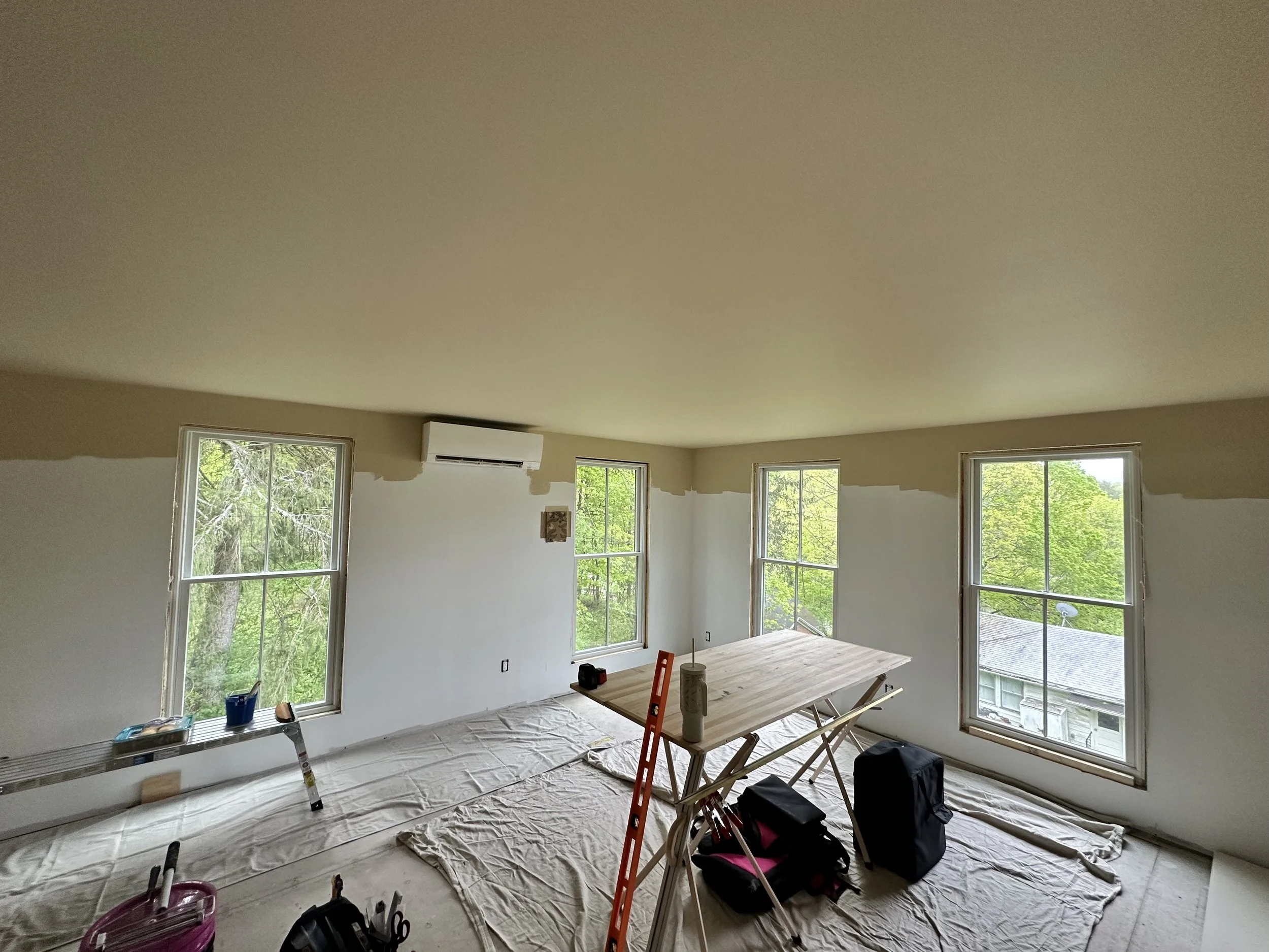 Wallpaper prep in progress in a light-filled Hudson Valley home, with tools and drop cloths set up for a full-room wallpaper installation.