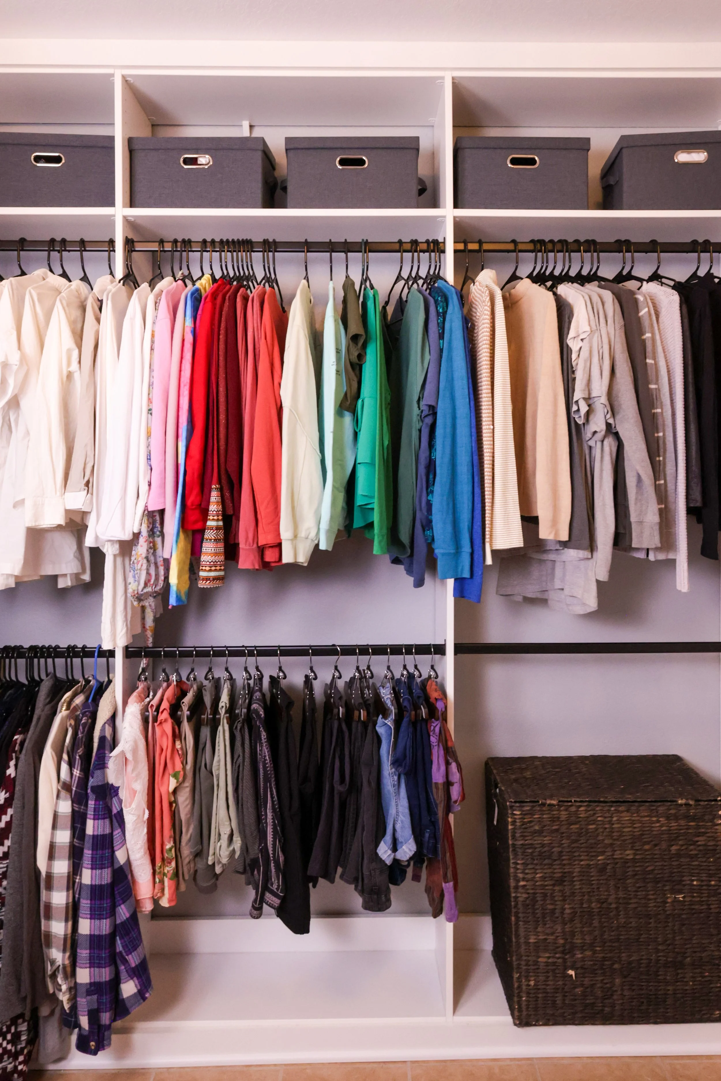 Professionally organized master closet with color coded clothes, custom shelves, and a woven storage basket on the floor in Frisco, Texas