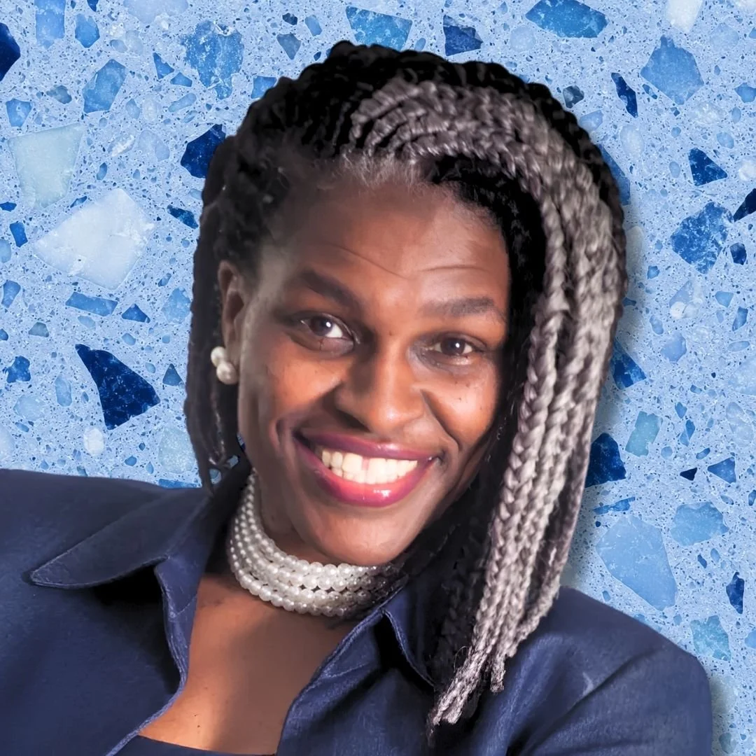 Close-up portrait of a smiling woman with braided hair, pearl earring, and layered pearl necklace, wearing a dark blue shirt, against a blue terrazzo background.
