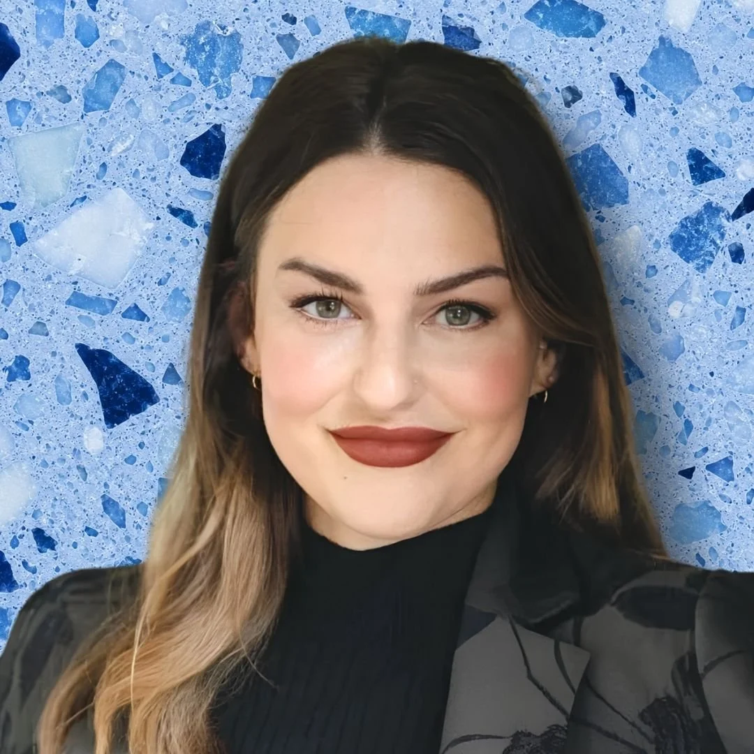 A woman taking a selfie in front of a blue terrazzo wall.