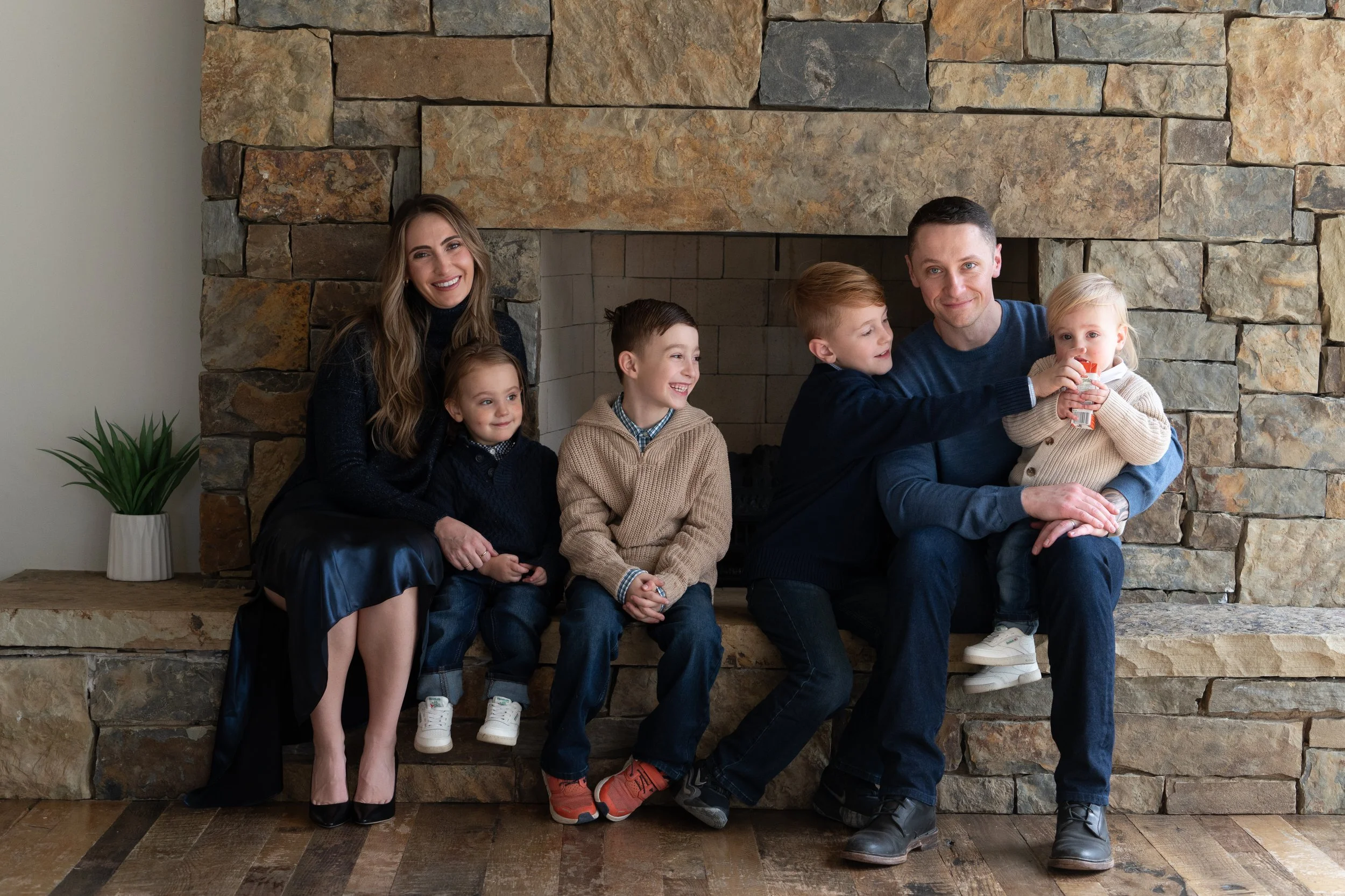 Family sitting by a fireplace, smiling and enjoying a moment together.