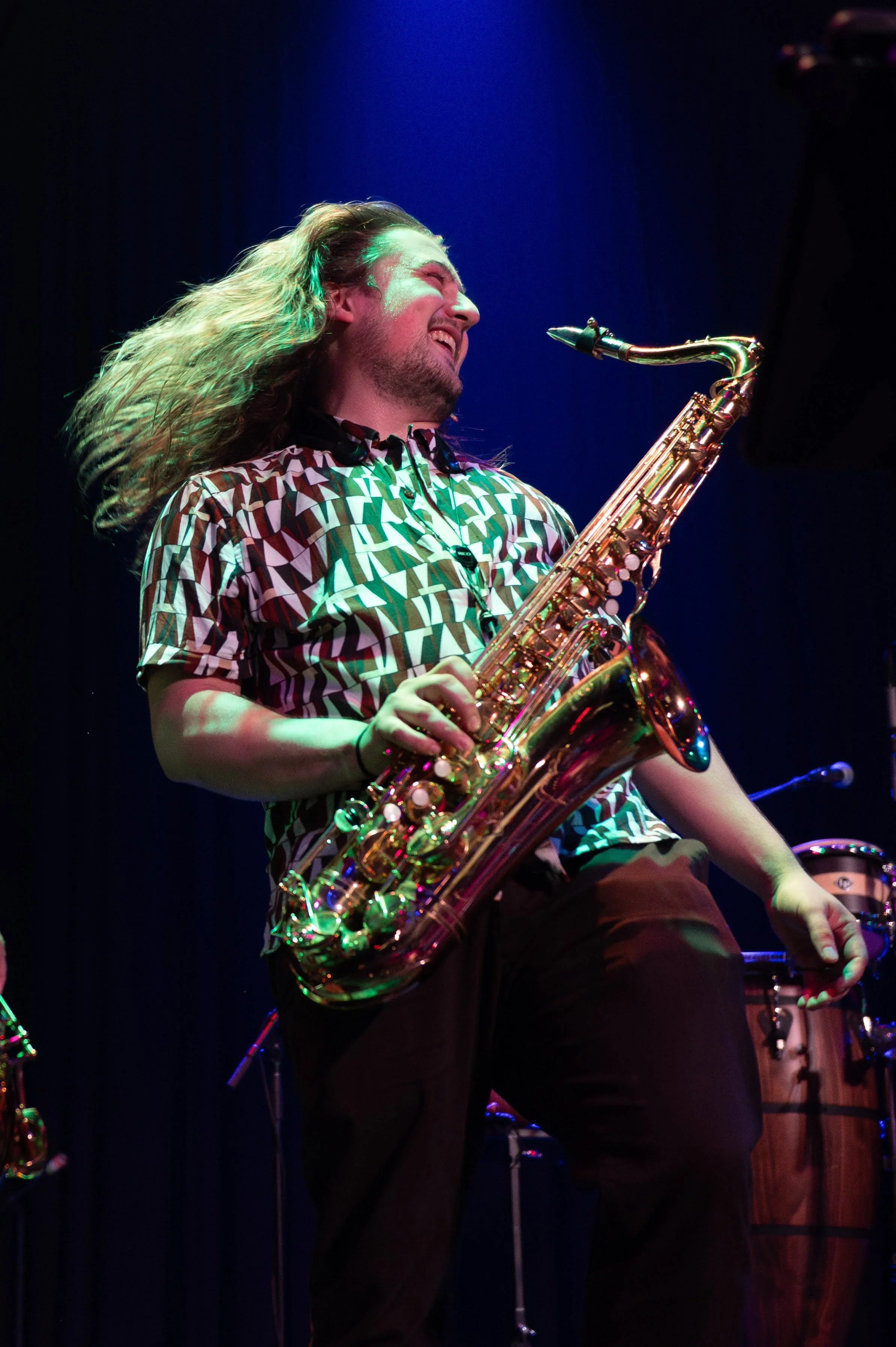 Musician playing a gold saxophone on stage with colorful lighting. Lancaster PA corporate celebration with Seraphina Soul delivering high-energy entertainment