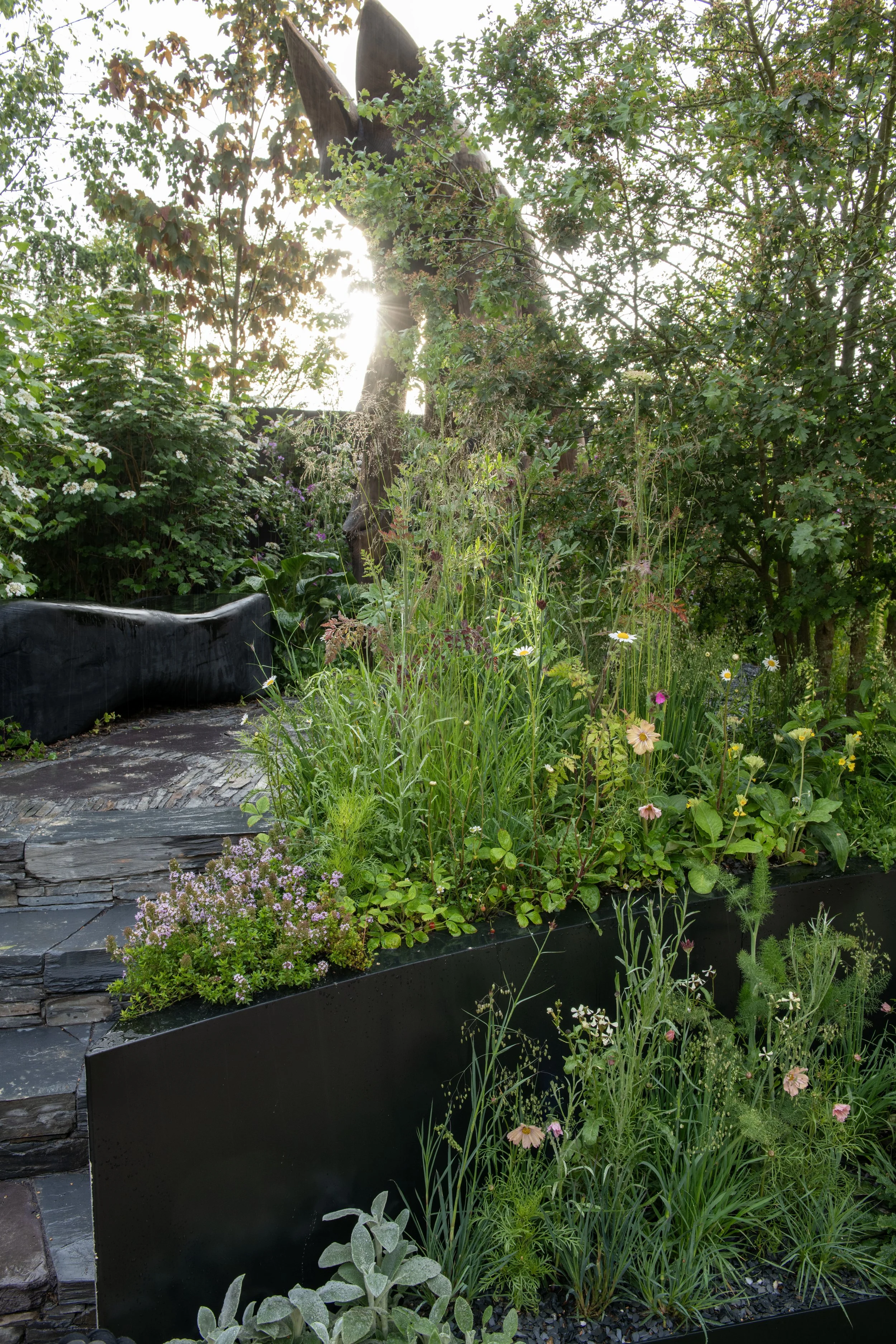 Bat-friendly garden design with a black bench slate paving and a black planter.