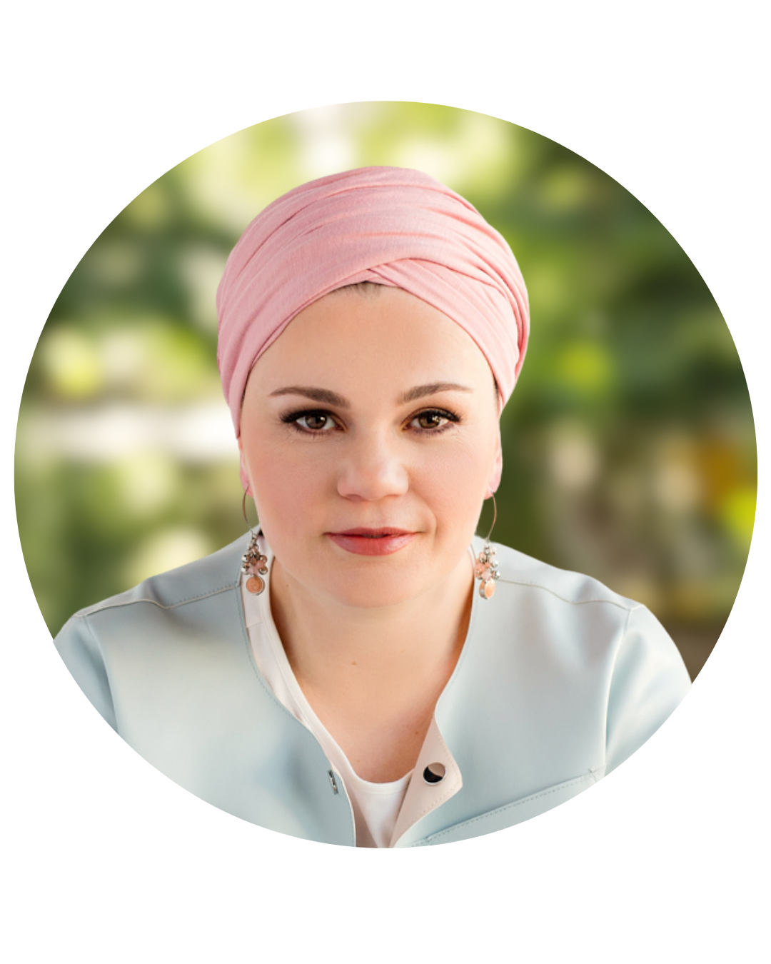 A woman wearing a pink headscarf with a blurred green outdoor background.