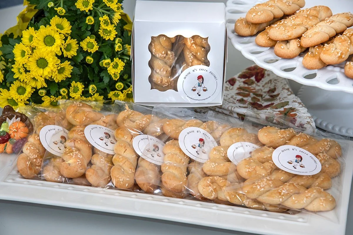 Auntie B's Greek Pastries wrapped and boxed sitting on a table with yellow flowers