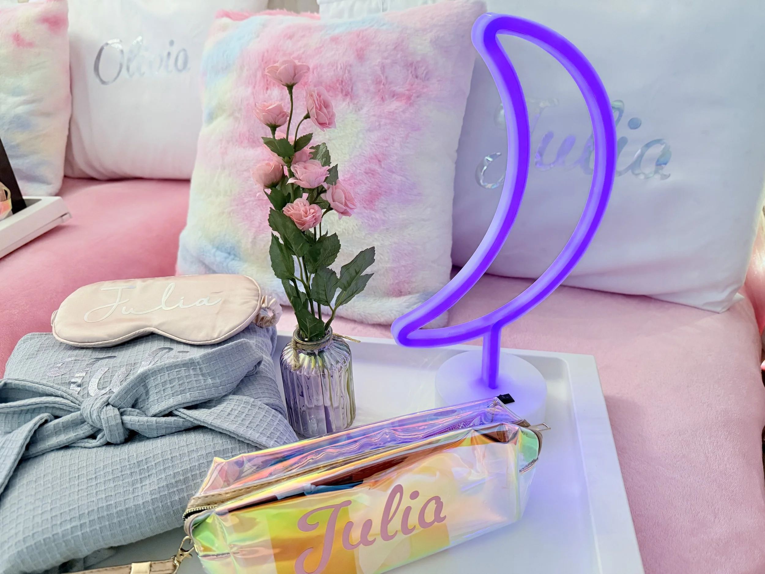 A pink bed with pastel tie-dye pillows and a white pillow with 