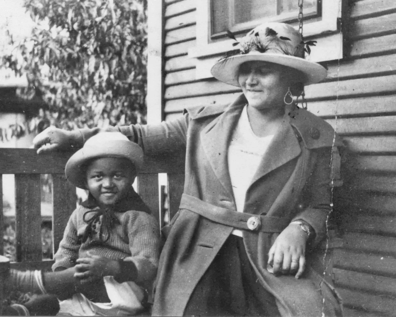 This photo provided by the Department of Special Collections, McFarlin Library, The University of Tulsa shows an African American woman and girl sitting on a porch swing, both dressed in coats and hats, by the side of a house. Provenance is unknown; 